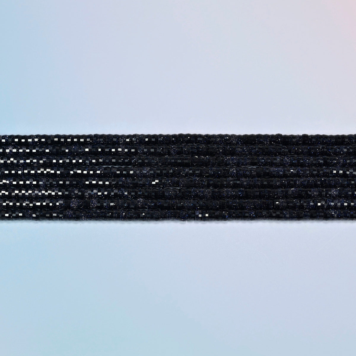 Several strands of blue sandstone faceted heishi disc beads laid in straight rows