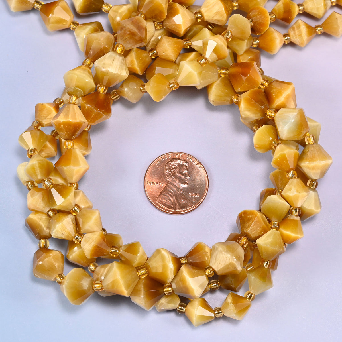 Gold tiger eye bicone beads coiled into a round ring, 8mm and 10mm sizes available, gold-tone spacers throughout.