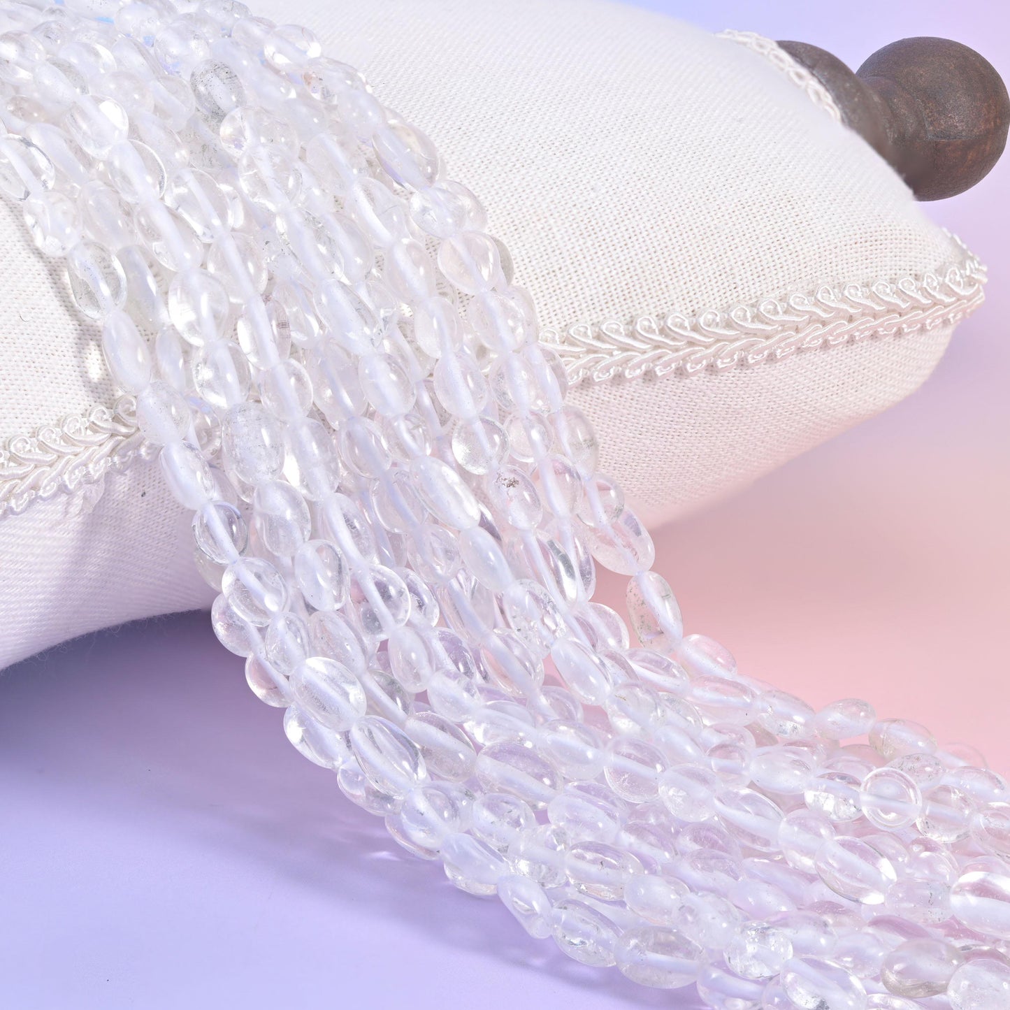 Clear quartz nugget strands on a white cushion, colourless glassy beads shot with milky veils