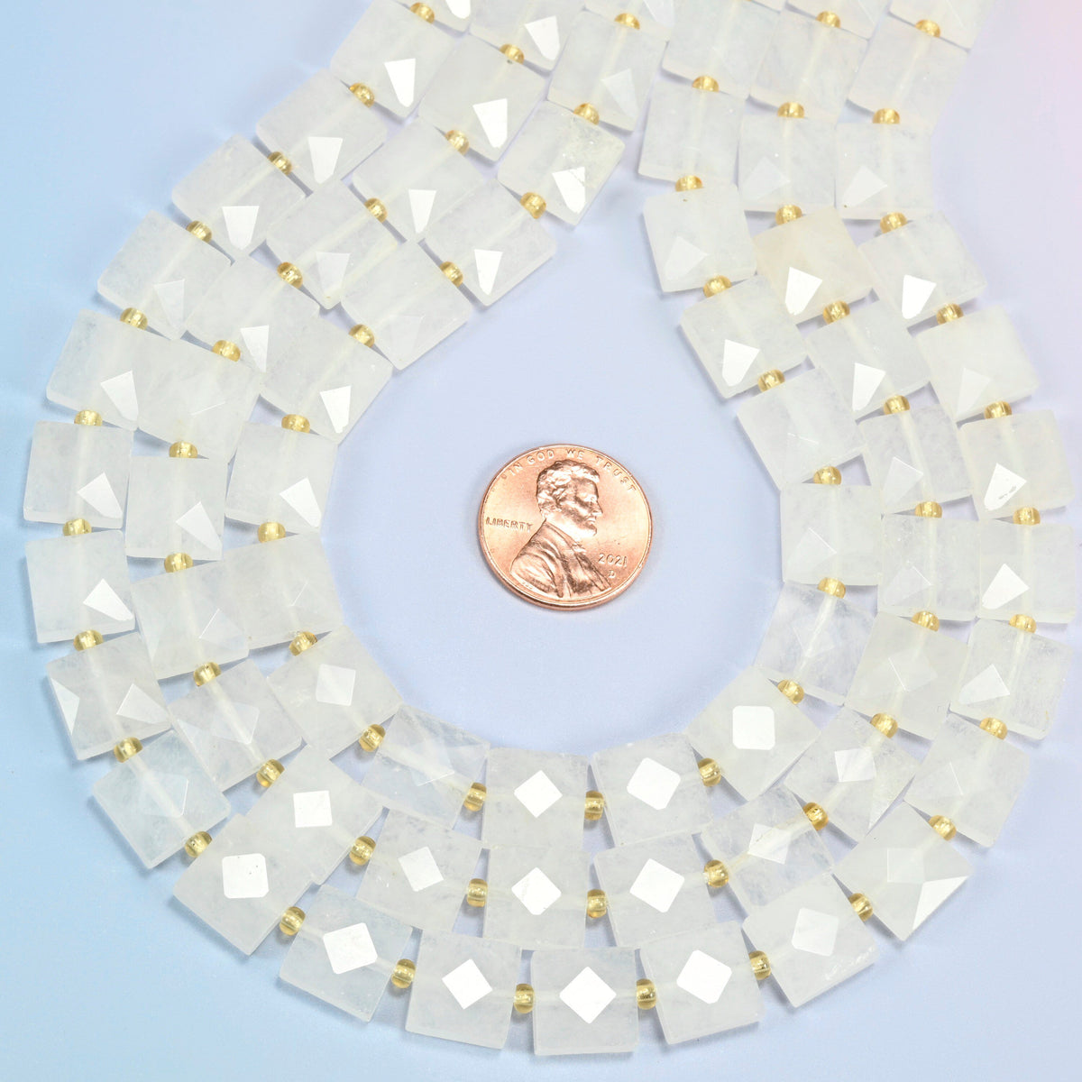 Clear quartz faceted flat square strands formed into a teardrop loop around a US penny for scale