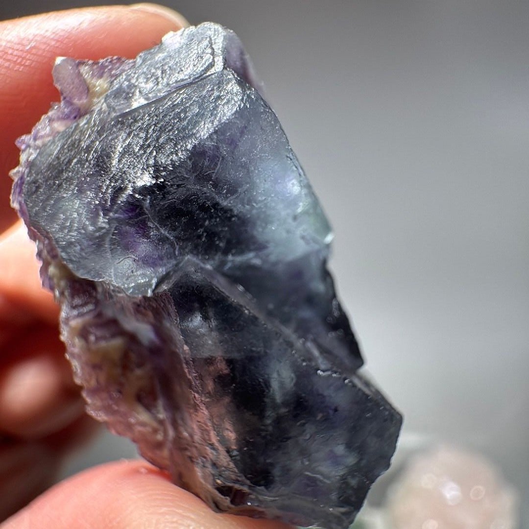 Hand-held Fluorite specimen showing glassy cleavage faces and purple zoning