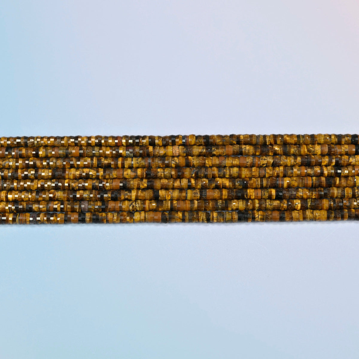 Several strands of tiger eye faceted heishi disc beads laid in straight rows