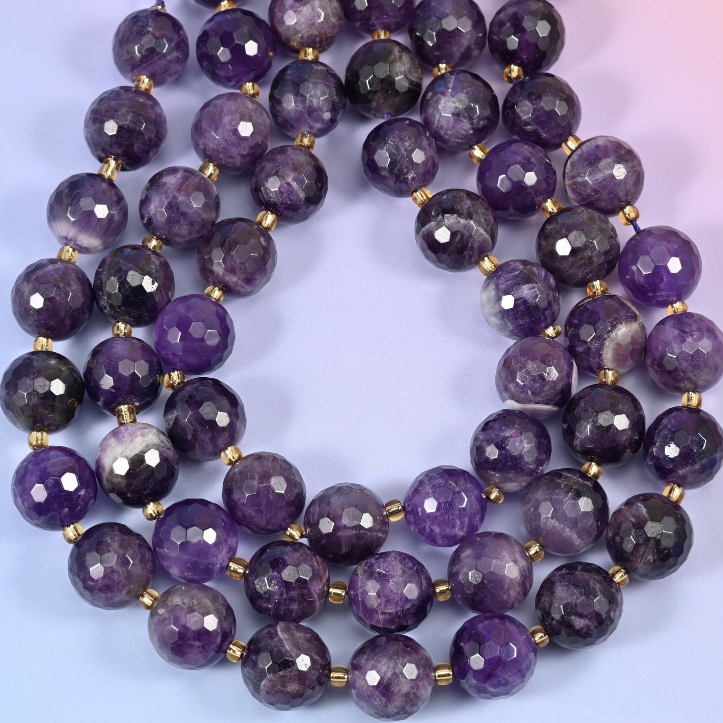Big deep violet rounds streaked with milky white and pale lavender banding, covered in small facets that scatter light across the purple and pick out the paler stripes.