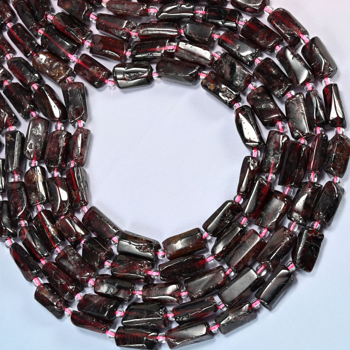 Red garnet tube beads curved into an open loop, dark red garnet with pomegranate red flashes