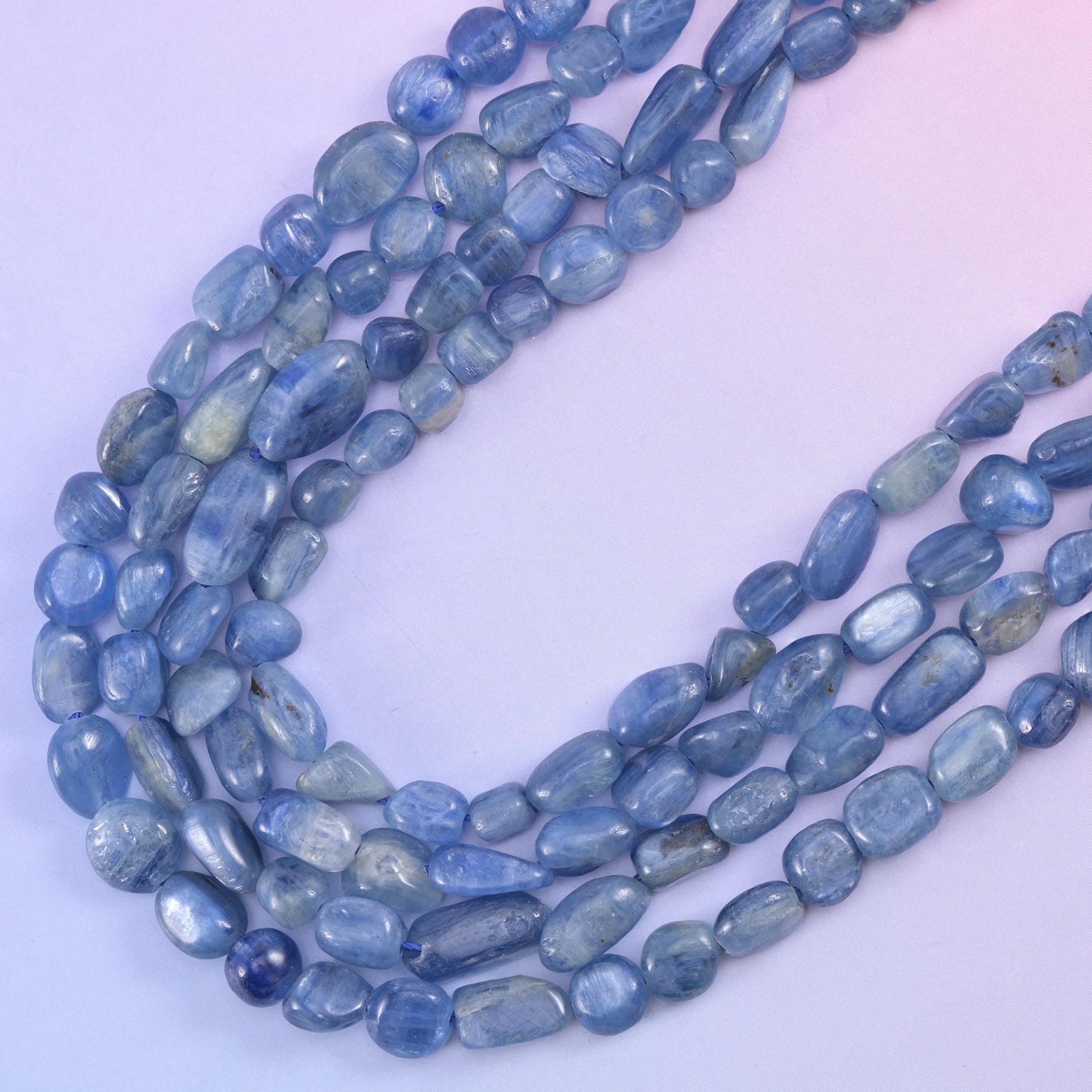 Loose loops of kyanite nuggets from above, colour shifting between grey-blue and deeper denim
