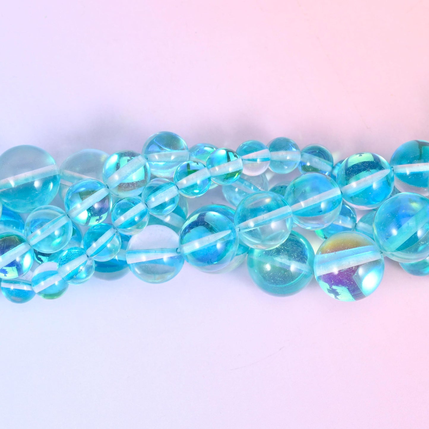 Clear aqua and sky blue rounds with a glossy polished surface, lit from inside by a green-blue rainbow flash