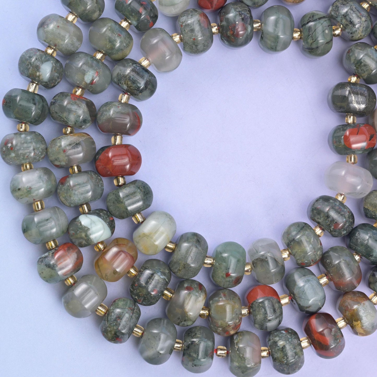 Overhead loop of pumpkin rondelle beads on a pale lavender surface