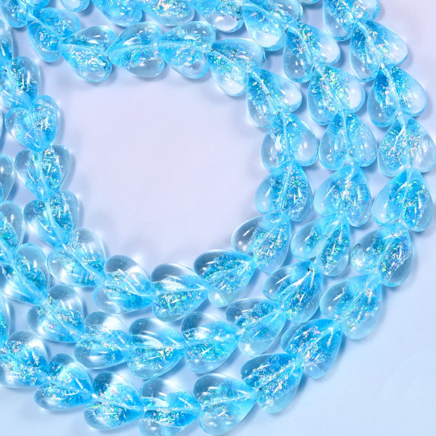 Iridescent light blue heart glass beads coiled in strands, light blue glass with silver and gold shimmer