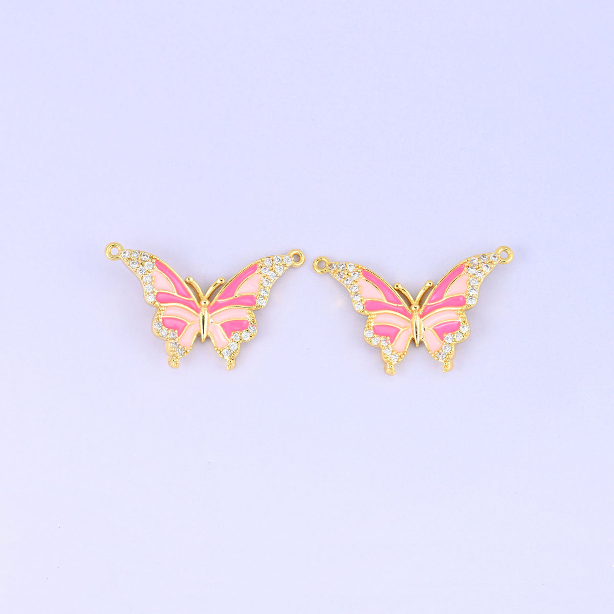 Enamel butterfly double connector pendants in pink, two gold plated charms with hot pink and blush wing stripes and a loop at each upper wing tip.