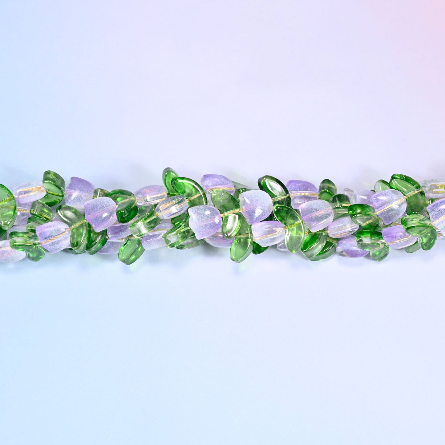 Circular coil of tulip and leaf glass bead strands on a lavender background with a penny in the center for size comparison.