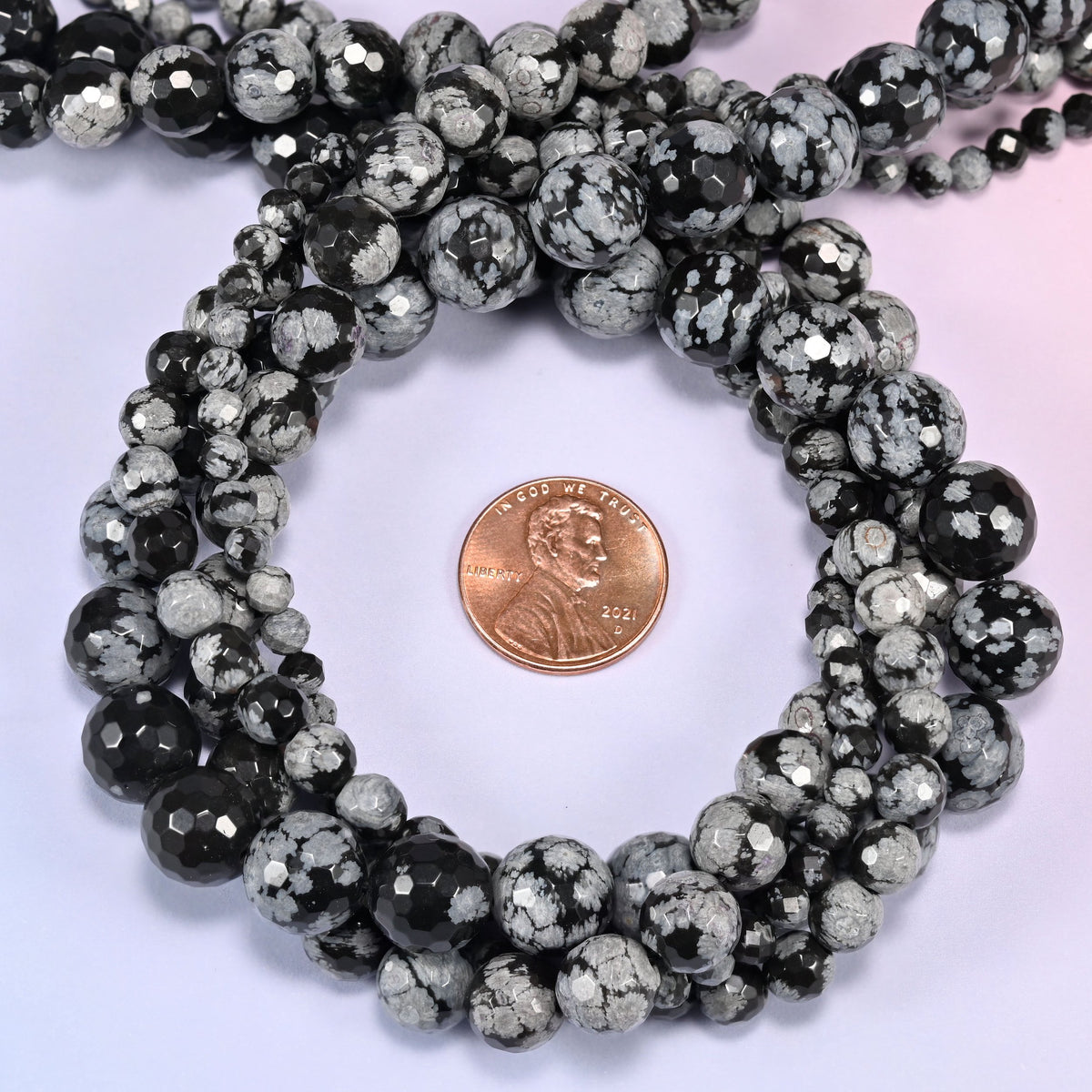 Snowflake Jasper faceted round beads coiled into a loop with a penny placed in the center for size reference.