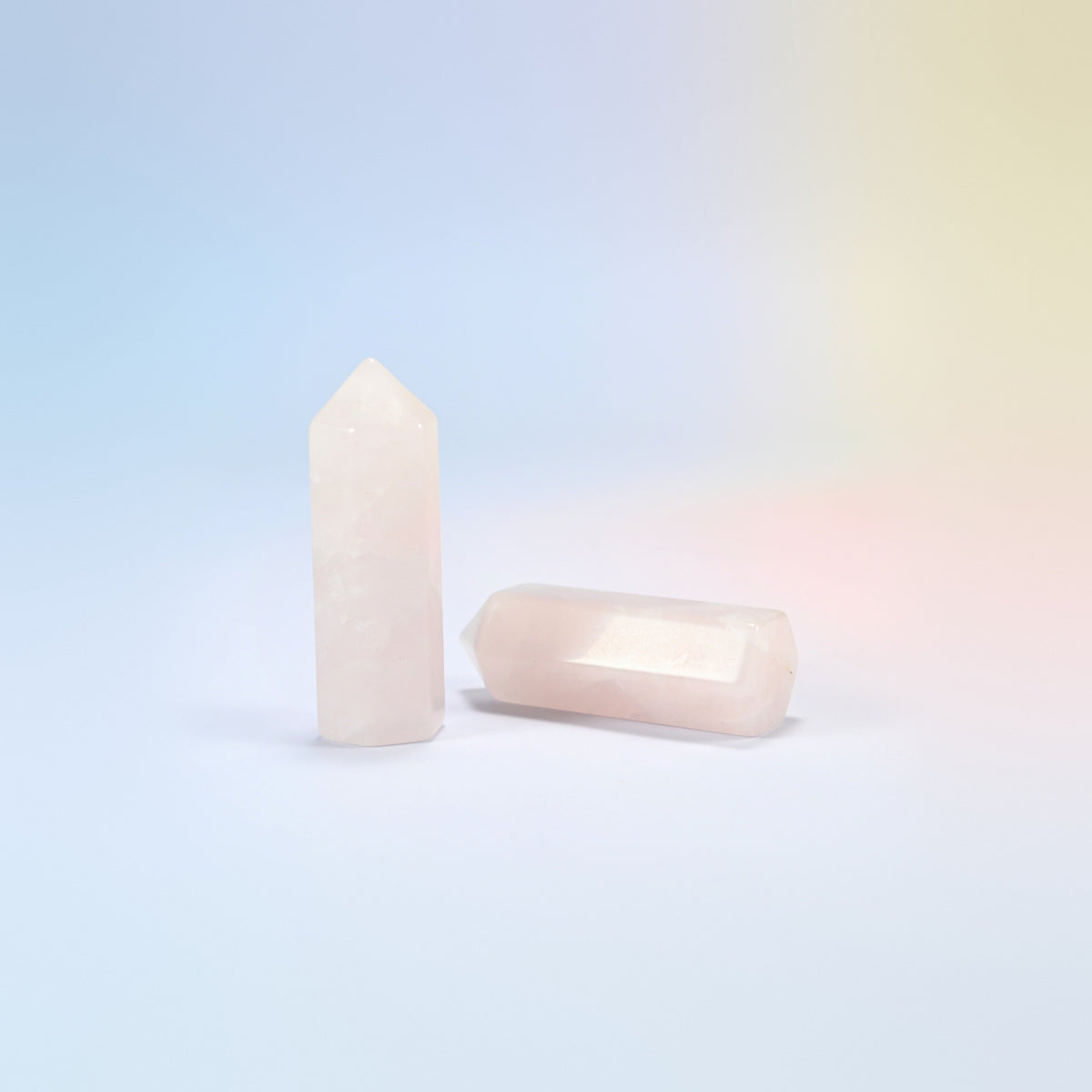 Natural rose quartz hexagon points in light pink, one standing and one lying down
