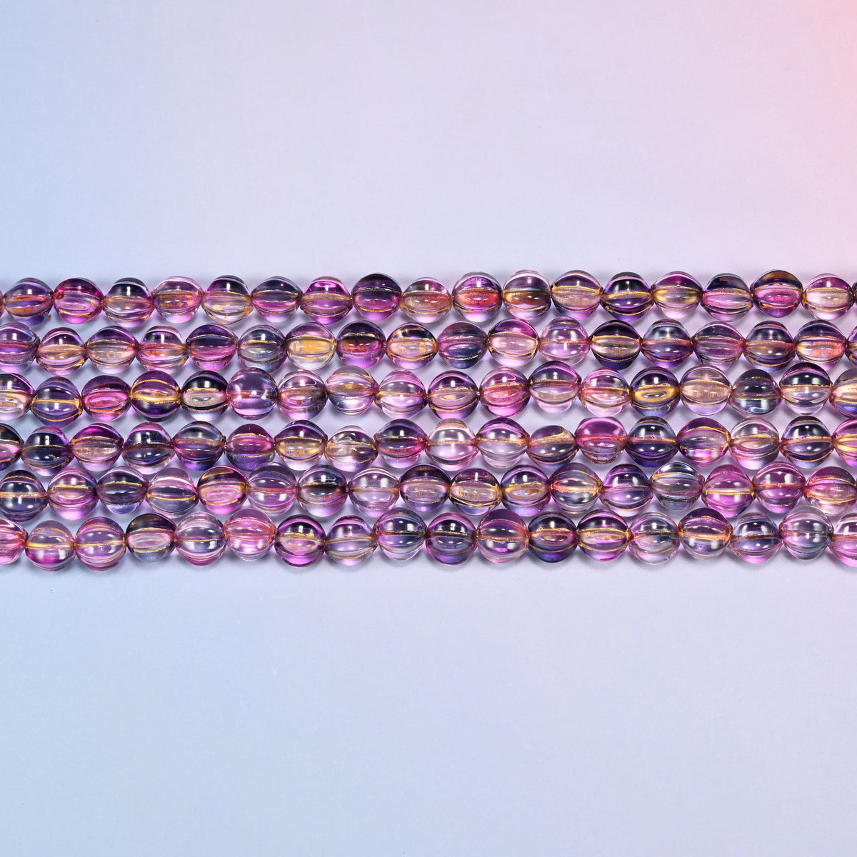 Close-up of 8mm pink blue gold pumpkin glass beads in four horizontal rows, showing the carved melon ribs.