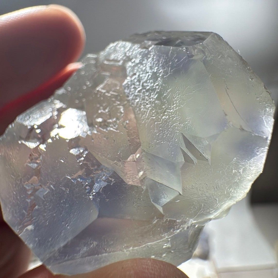 Close hand-held view of the fluorite crystal, blue patches under a green surface