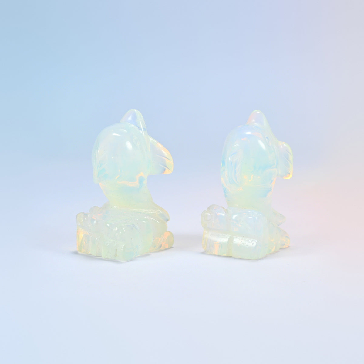 Two opalite dolphin figurines from behind showing the wave detail