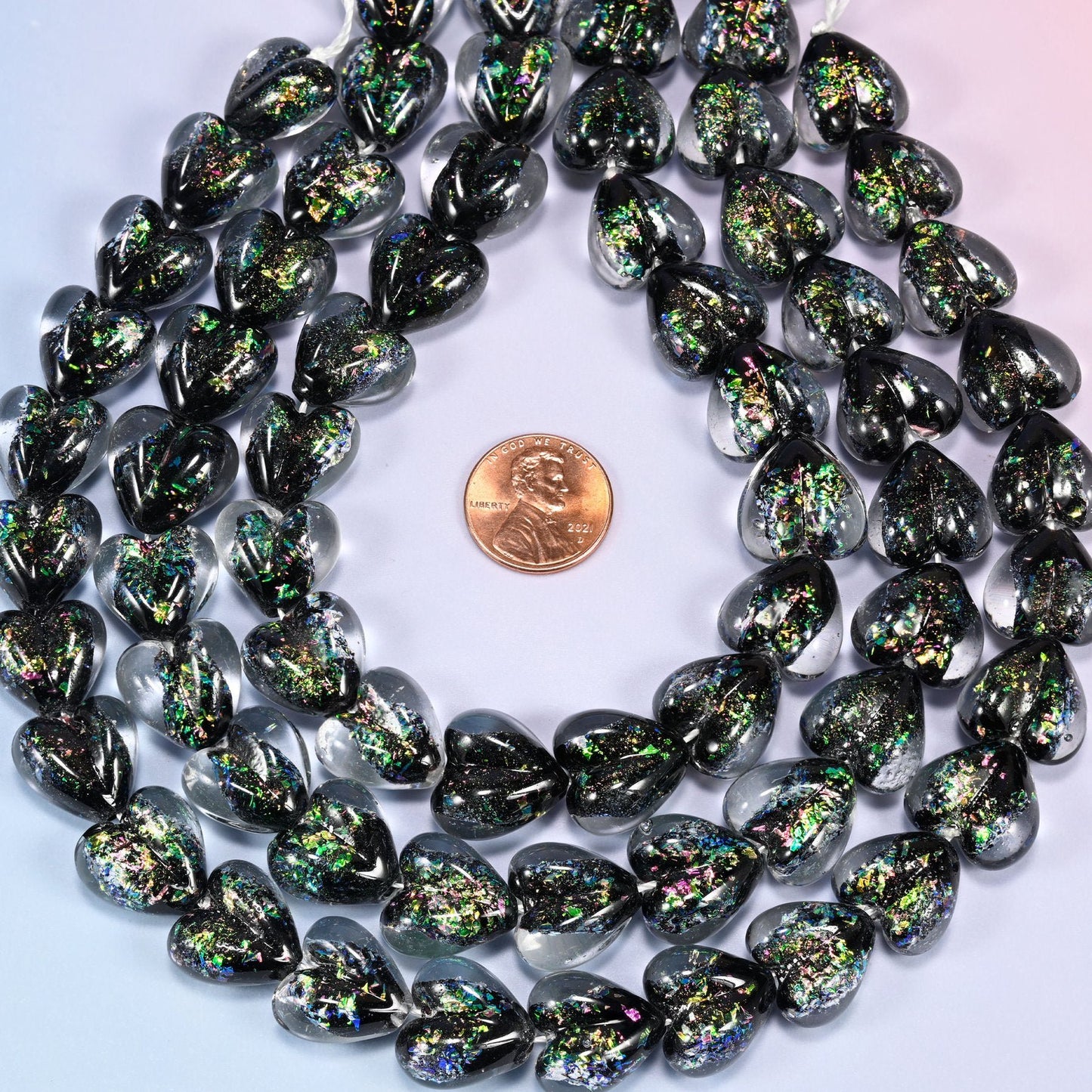 Puffed glass hearts that read near-black, breaking into flecks of emerald, gold and violet glitter