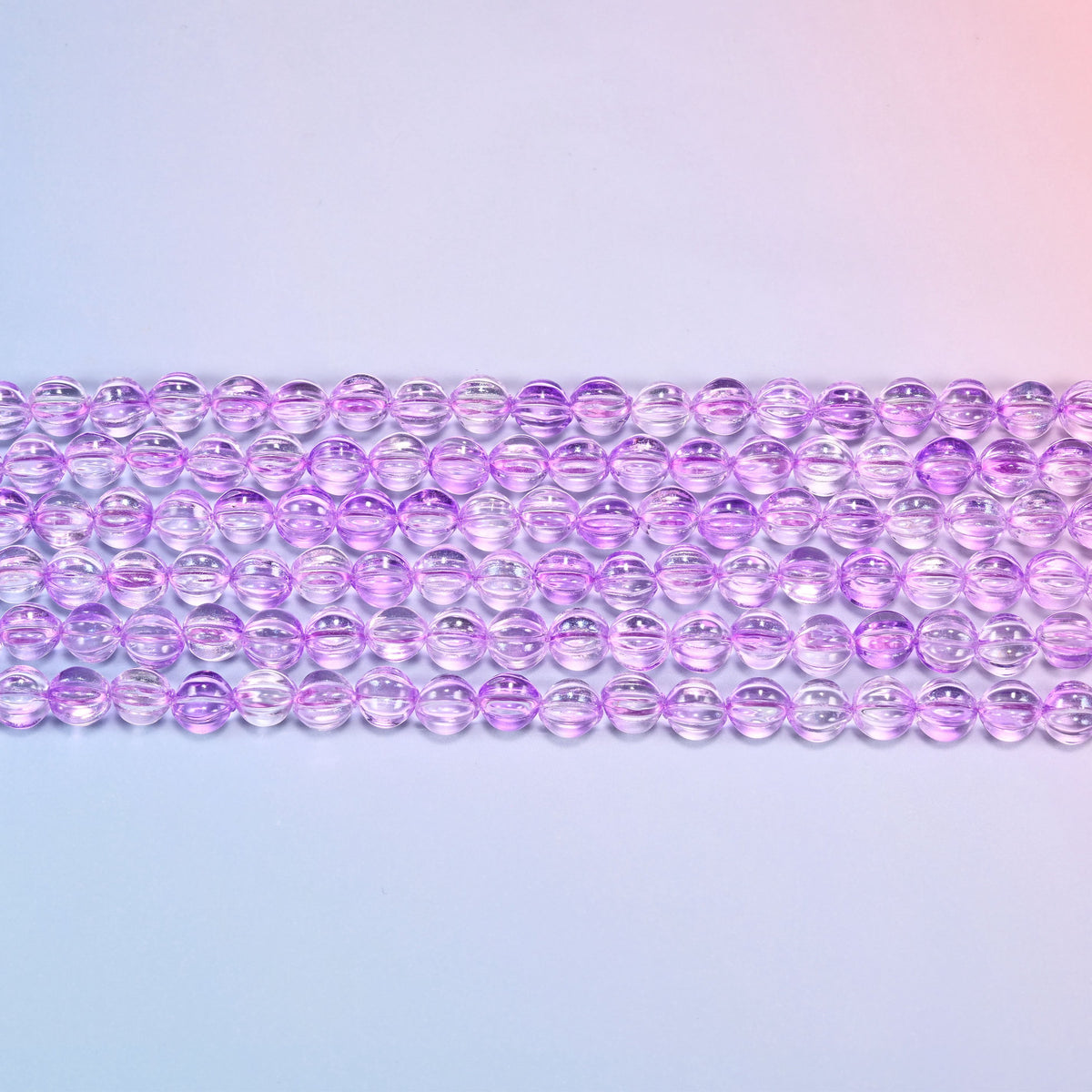 Close-up of 8mm clear purple pumpkin glass beads in four horizontal rows, showing the carved melon ribs.