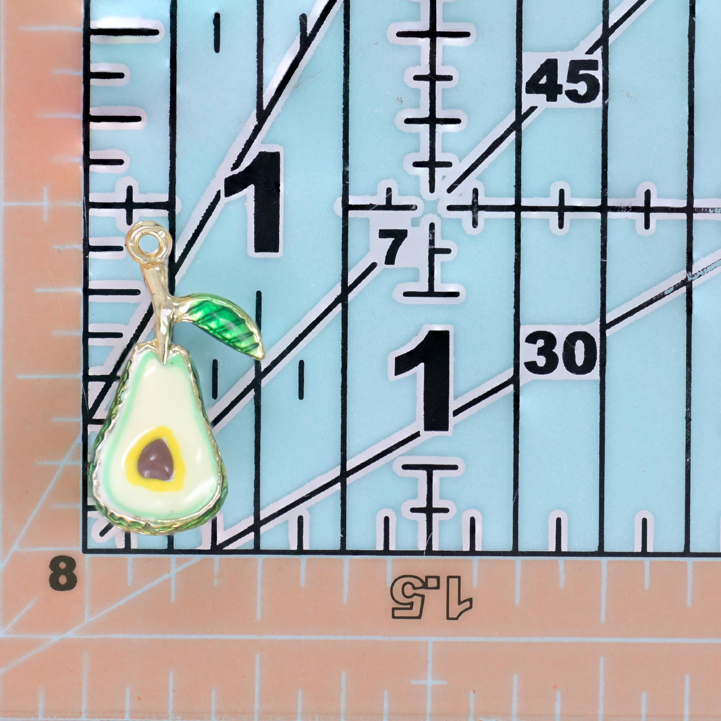 A chunky enamel avocado with a textured deep green skin and a striped green leaf on a gold stem
