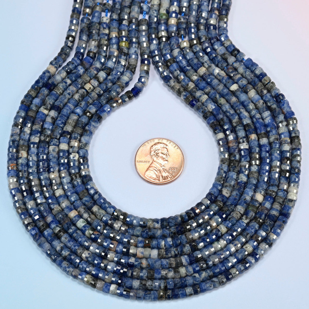 Sodalite faceted heishi disc strands formed into a teardrop loop around a US penny for scale