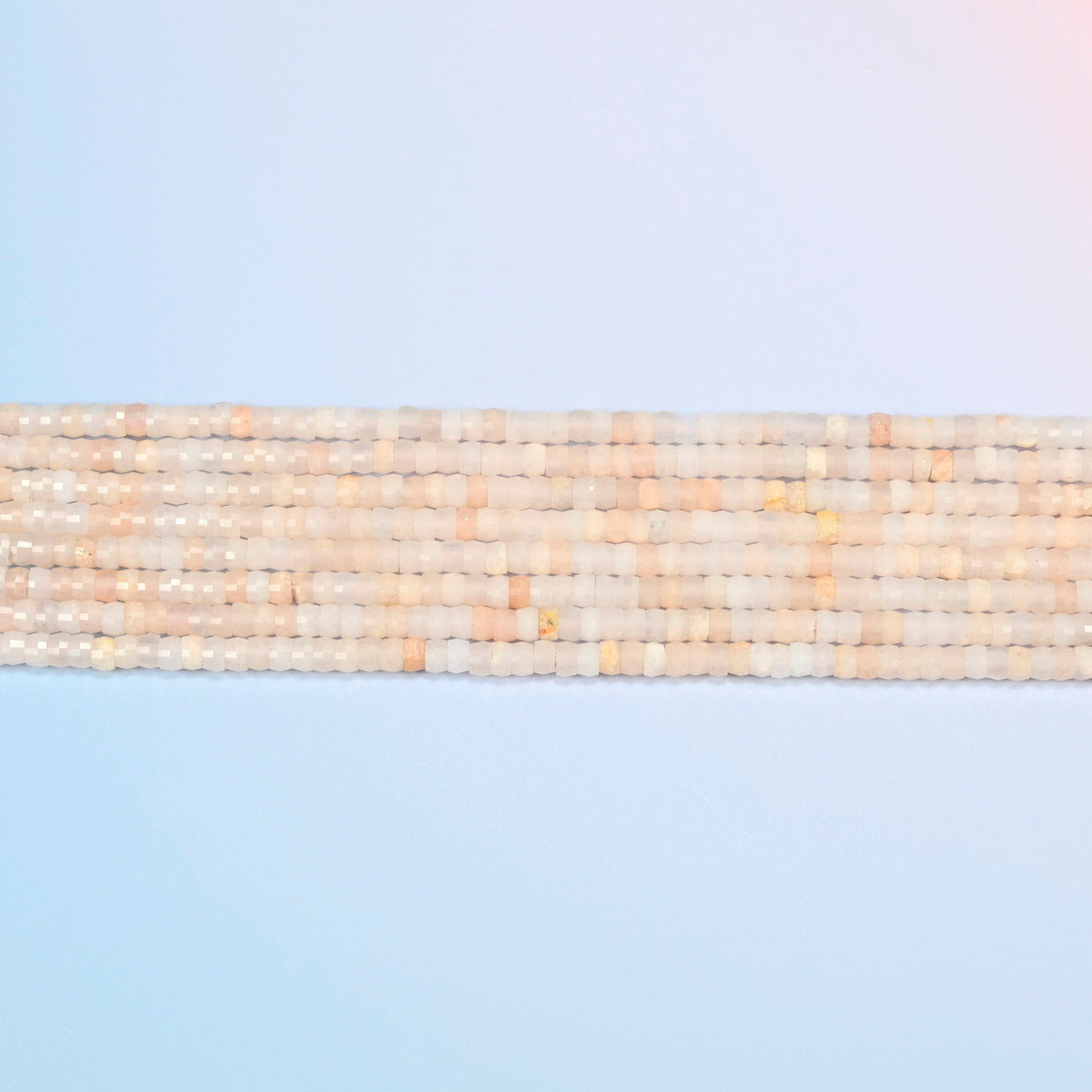 Several strands of pink aventurine faceted heishi disc beads laid in straight rows