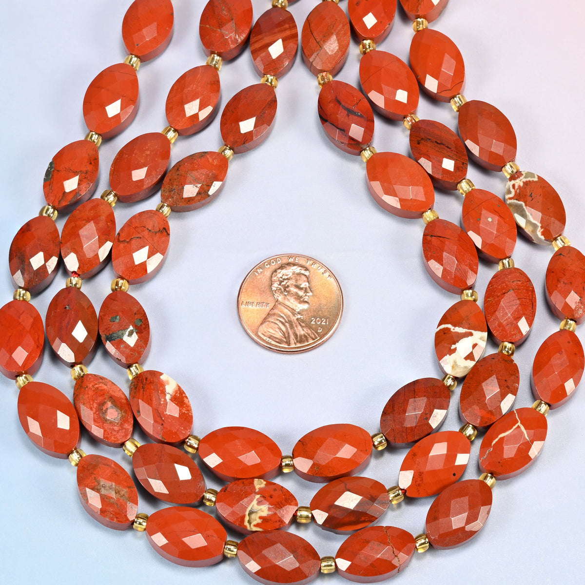 Flower red jasper faceted flat oval strands formed into a teardrop loop around a US penny for scale