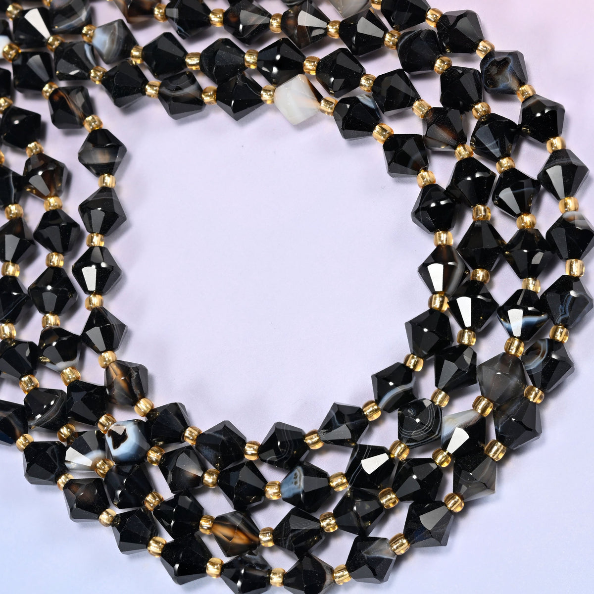 Dyed black strip agate bicone beads formed into a wide open ring, a few beads showing a warm brown-gray stripe through the black.