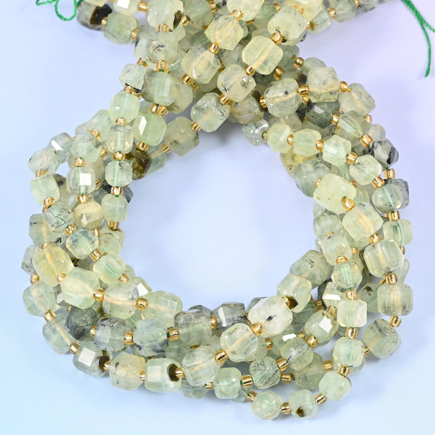 Pale celadon and lemon-tinged green cubes, translucent enough to glow from the inside, freckled with dark green and near-black mineral inclusions.