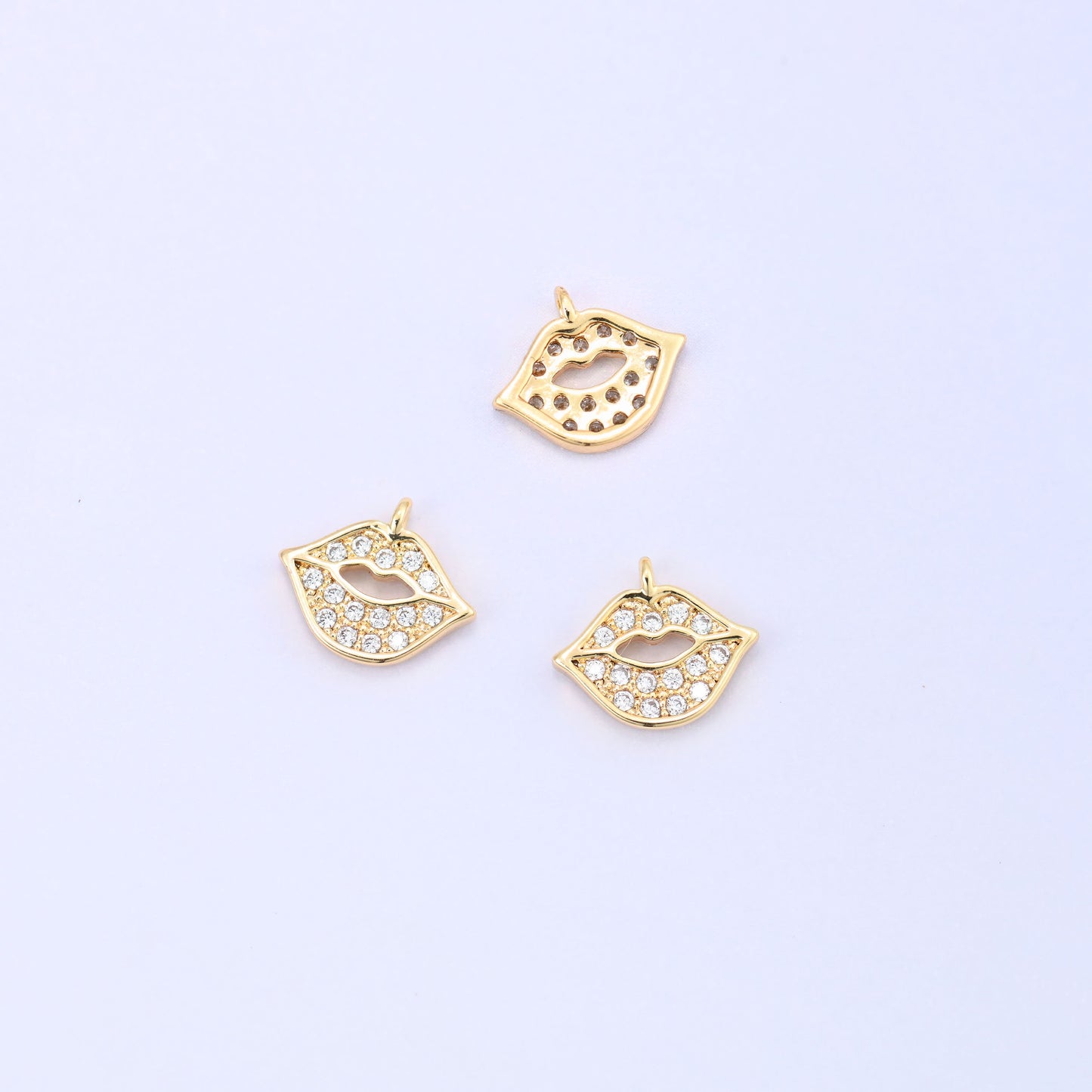 Small gold charms, three gold plated lip charms with one turned to show the plain back