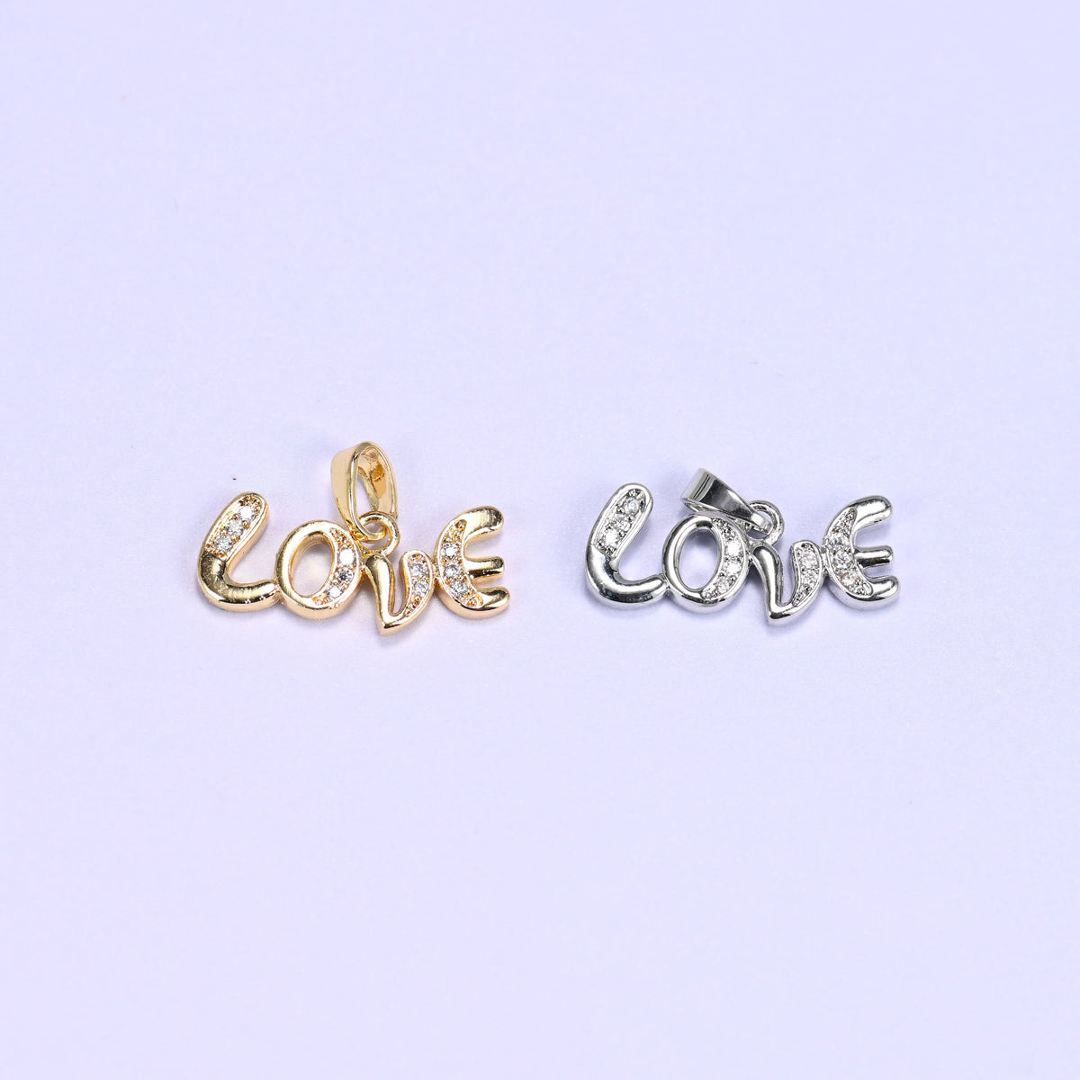 Love letter zirconia charm colour comparison: one 18K gold plated Love script pendant beside the same design in platinum-tone silver.