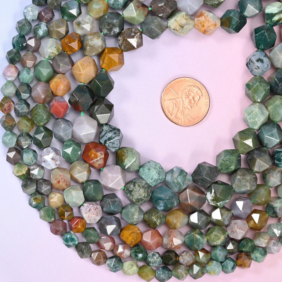 Indian Agate diamond star cut beads coiled around a US penny for size reference, centre drilled
