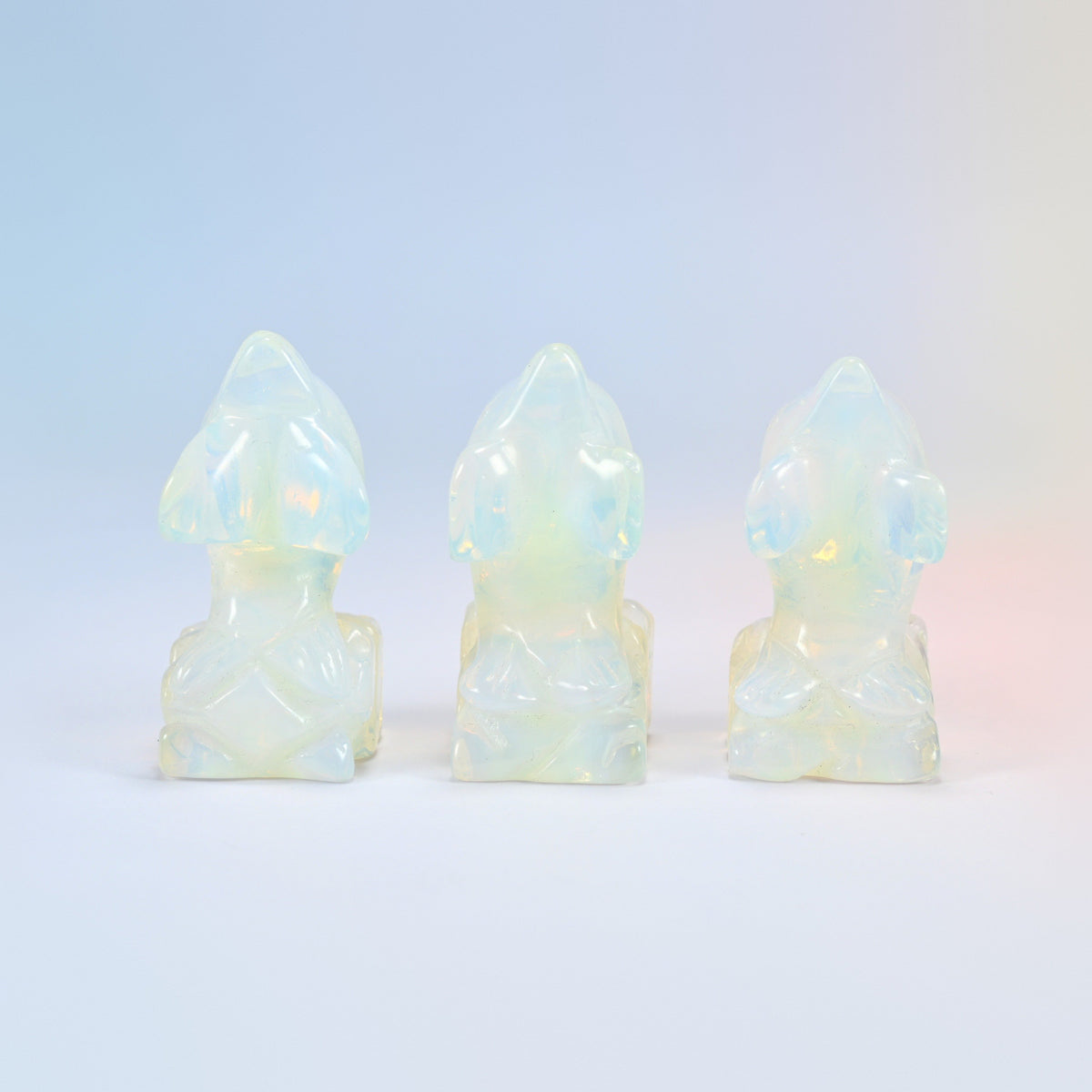 Front view of three opalite dolphin on wave figurines