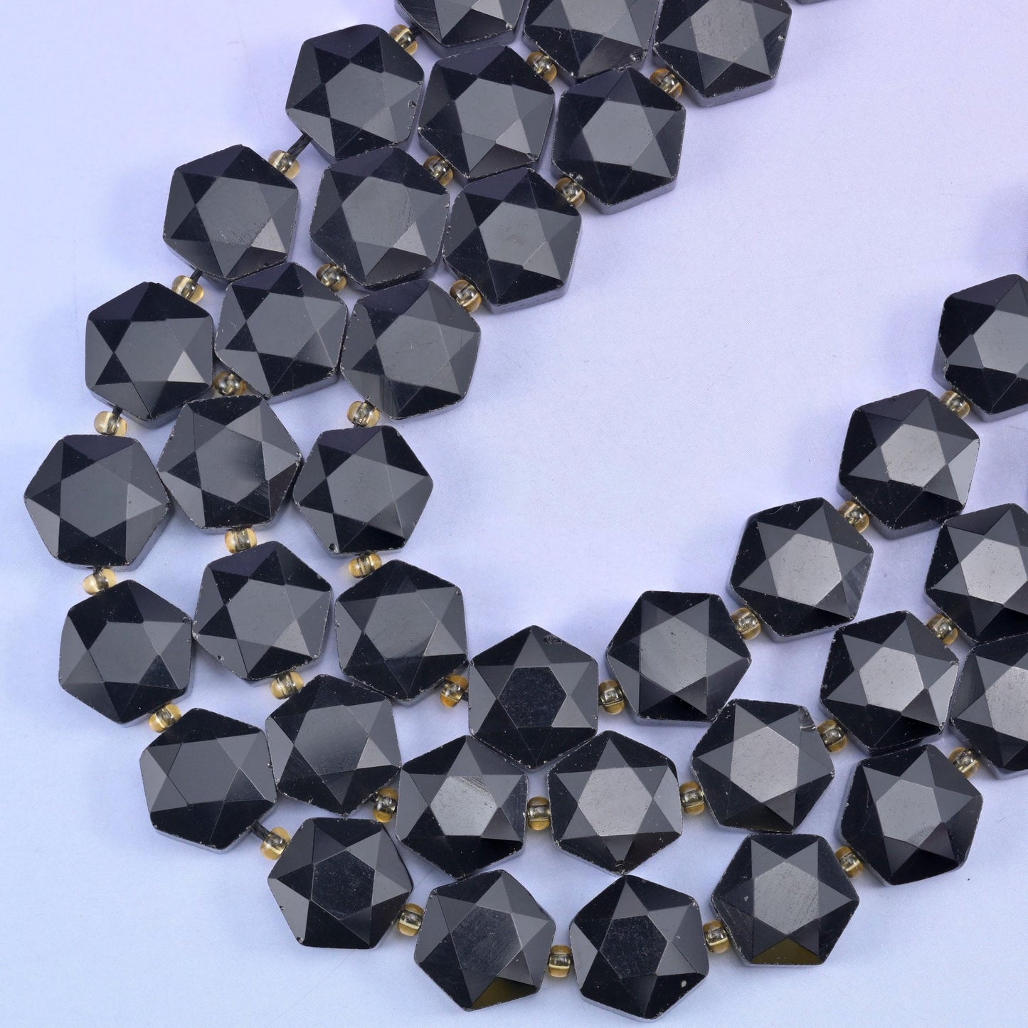Strands curving into a V, small gold-tone spacers separating each faceted hexagon on the cord