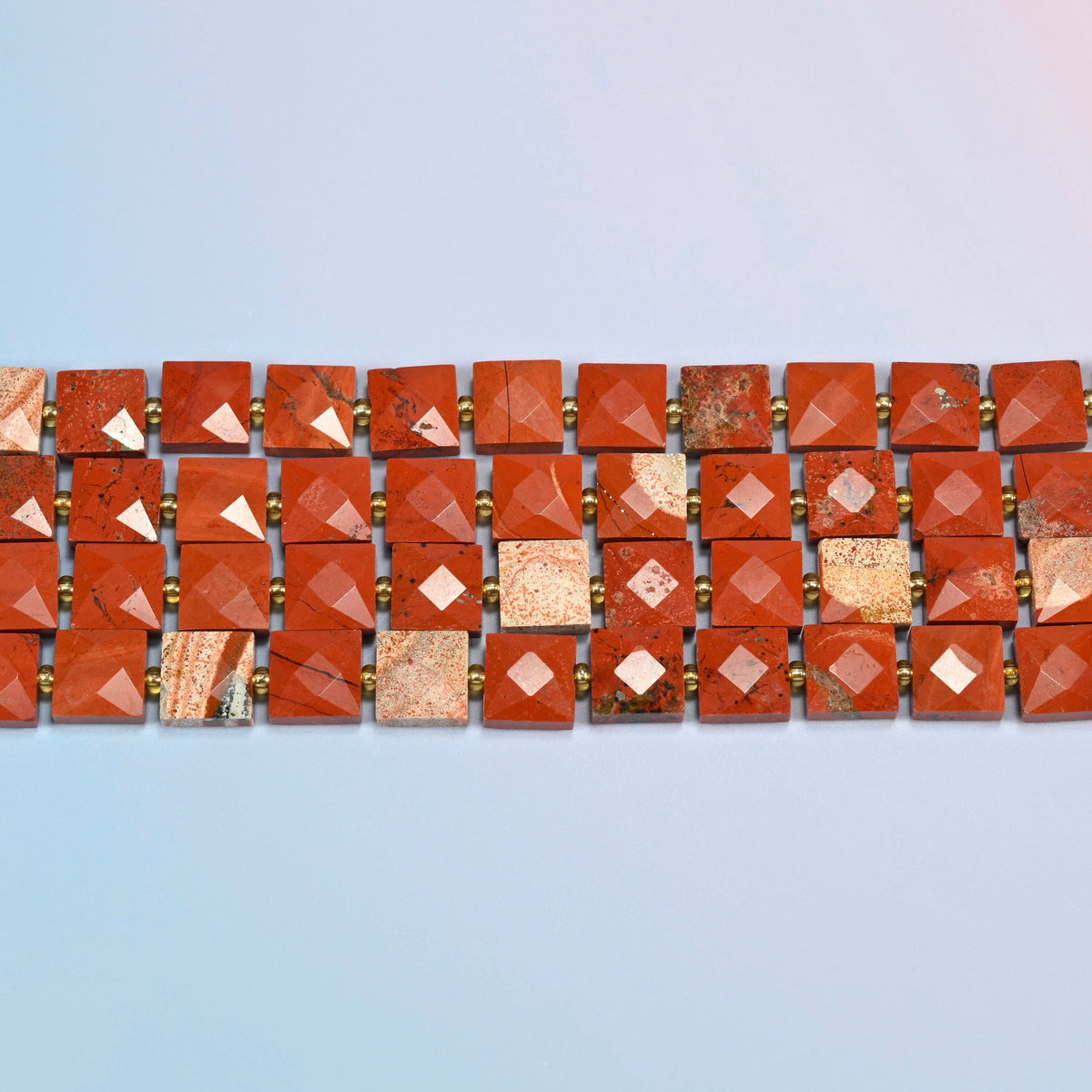 Several strands of natural flower red jasper faceted flat square beads laid in straight rows