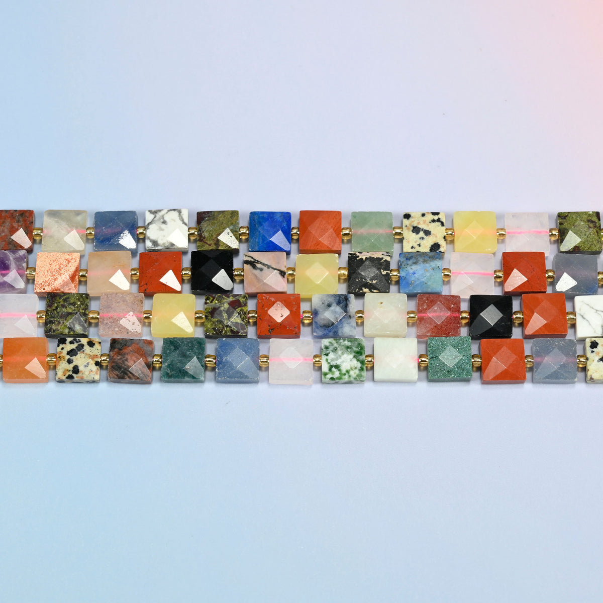 Several strands of assorted gemstone faceted flat square beads laid in straight rows