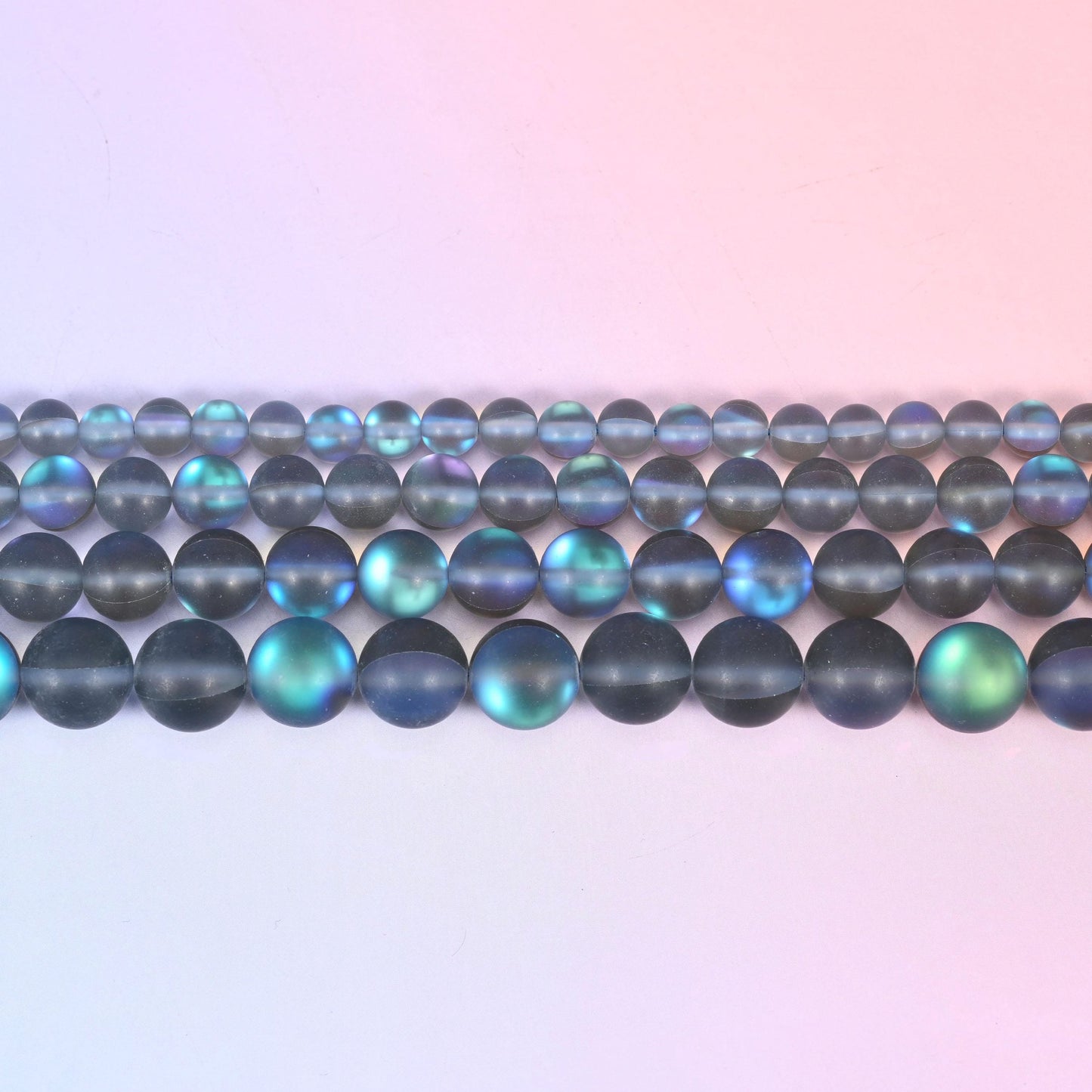 Matte glass beads in frosted smoke grey with a blue-and-green aurora shimmer