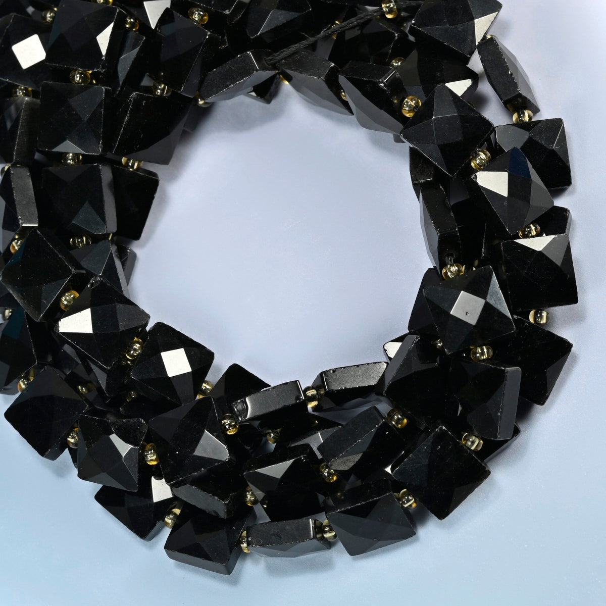 Natural black onyx faceted flat square beads coiled into overlapping loops, whole strands of solid black stone