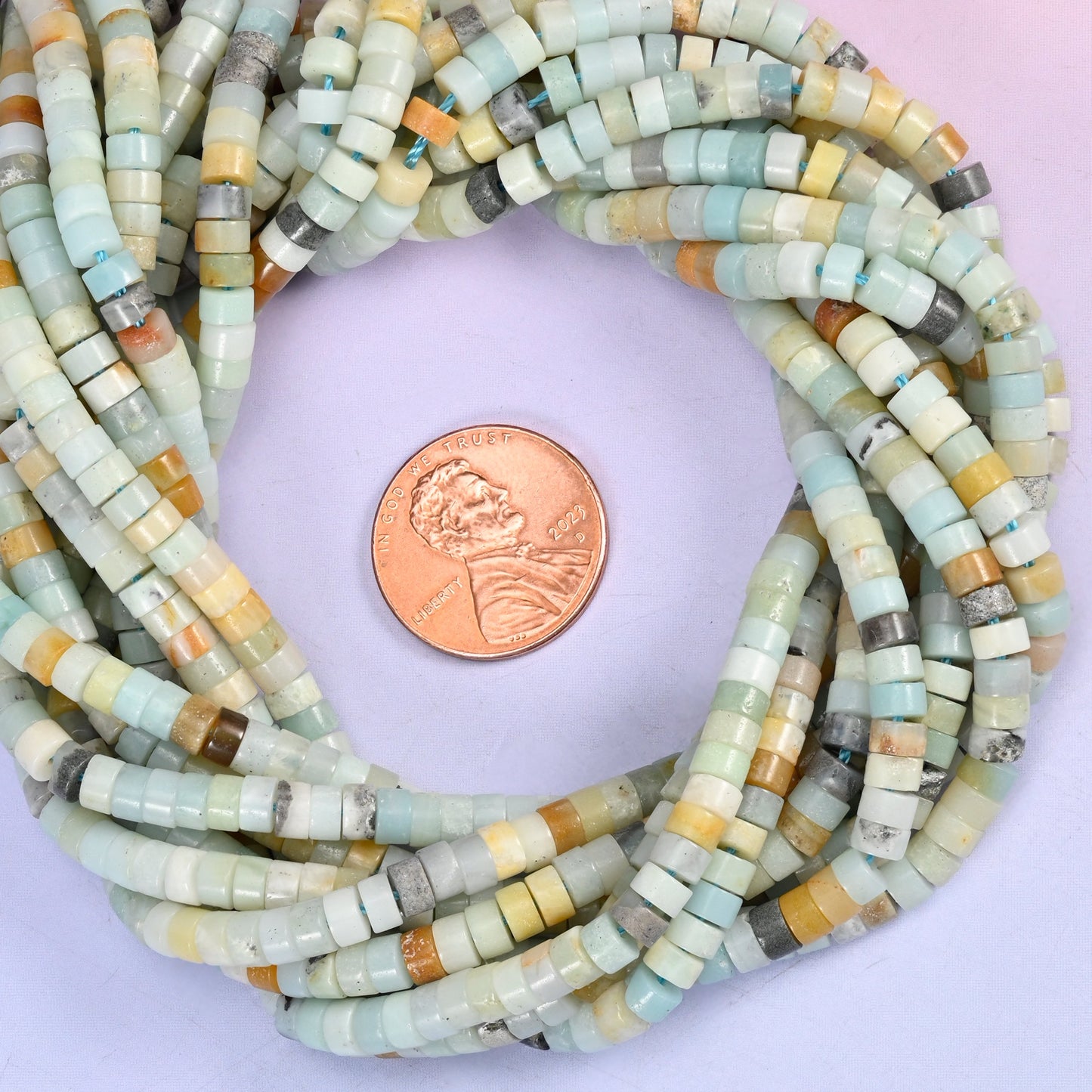 Multi-Color Amazonite smooth heishi disc bead strands coiled around a US penny for size reference
