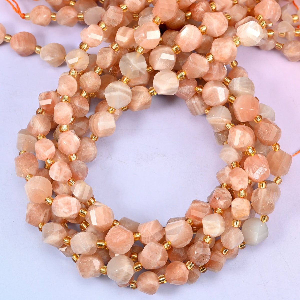 Orange Sunstone faceted spiral twist beads, close view of the coiled strands in peach and cream with gold spacer beads