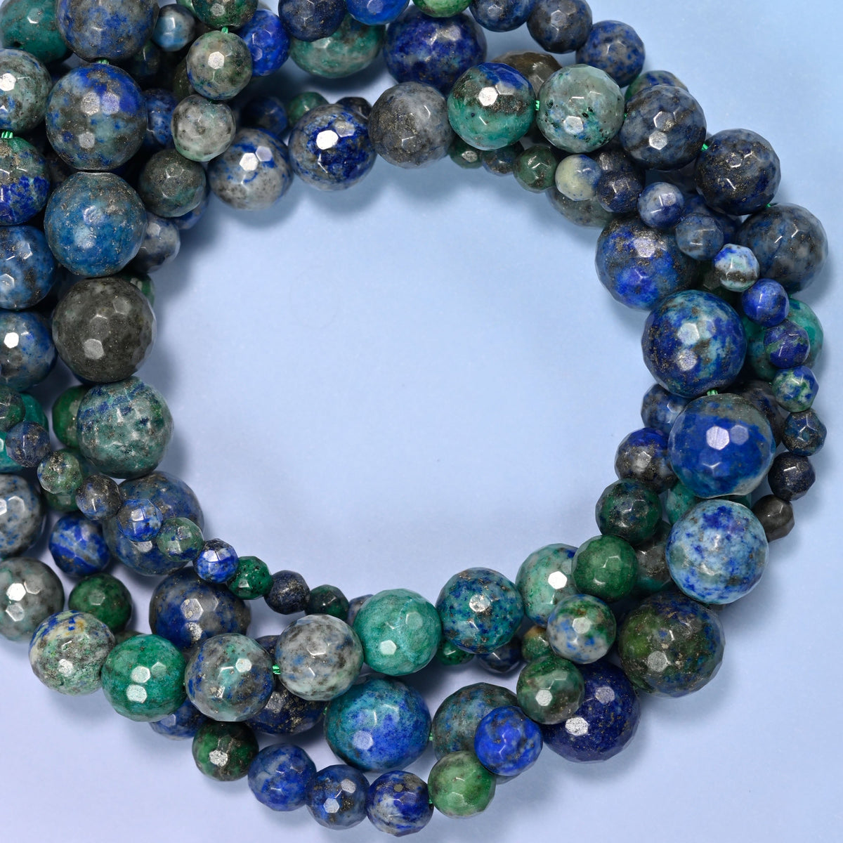 Phoenix Lapis faceted round beads, close view of the coiled strands showing deep blue, green and grey