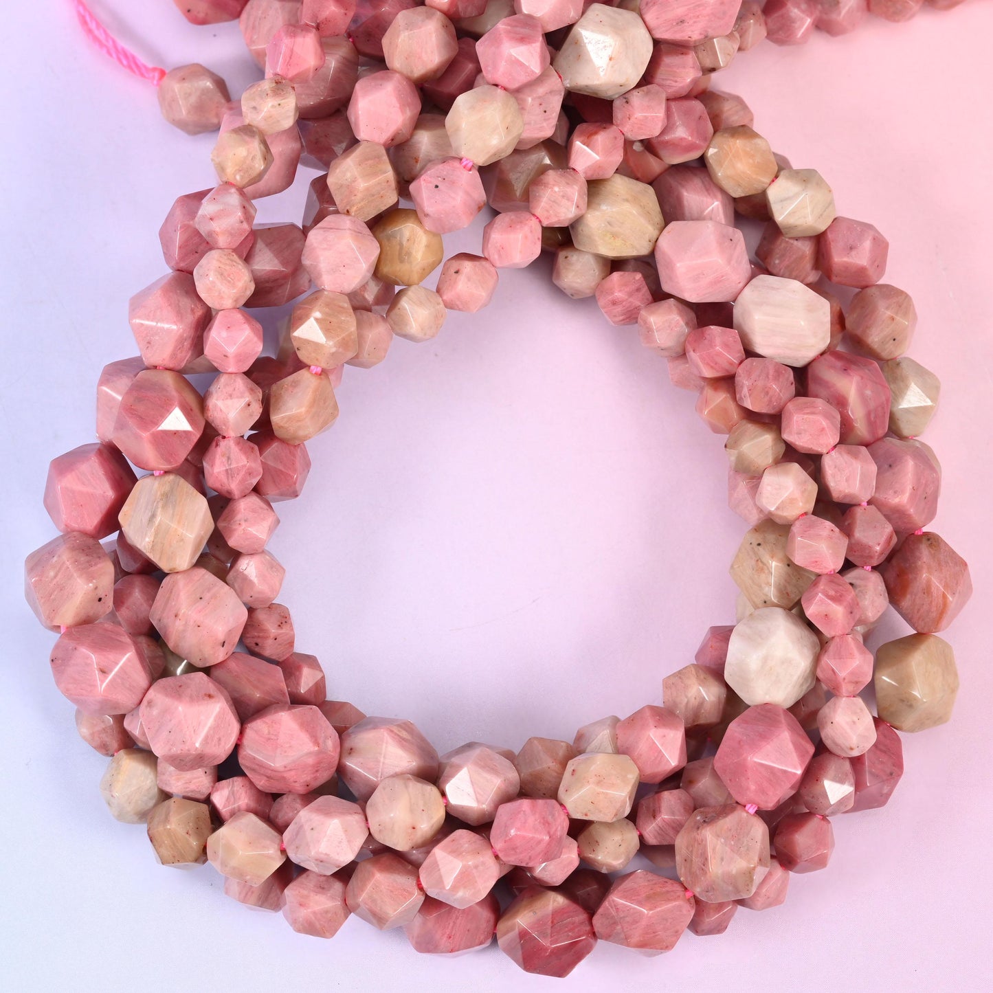 Pink Rhodonite faceted diamond star cut beads, close view of the coiled strands showing dusty rose pink and tan