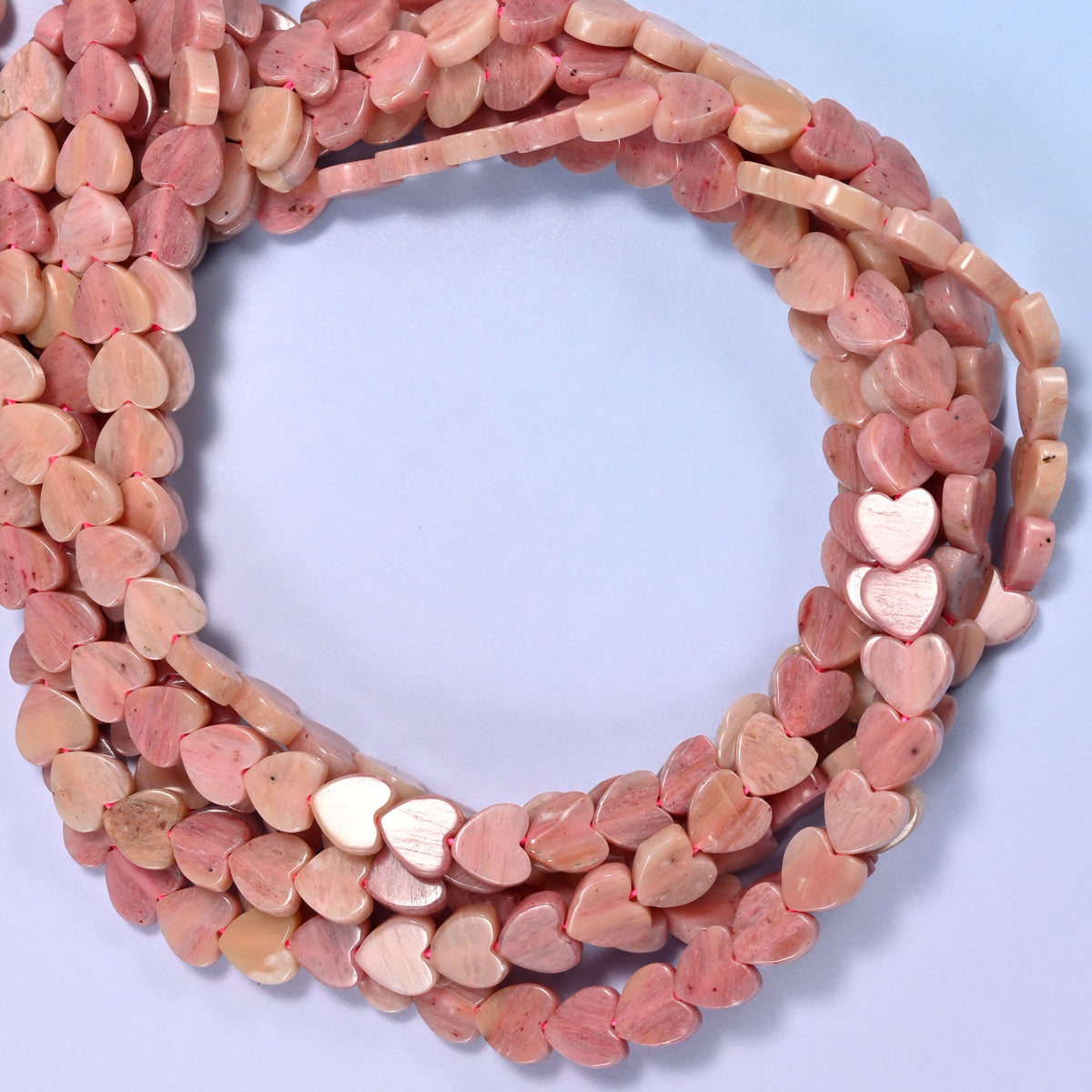 Pink Rhodonite flat heart beads, close view of the coiled strands in dusty pink with cream
