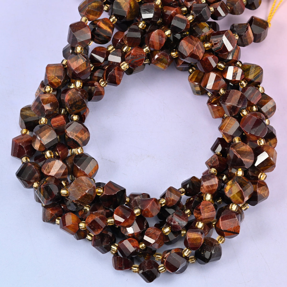 Red Tiger Eye faceted spiral twist beads, close view of the coiled strands showing deep red-brown bands with darker stripes