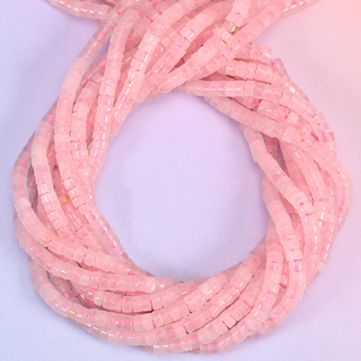 Rose Quartz smooth heishi disc beads, close view of the coiled strands showing the soft pink colour