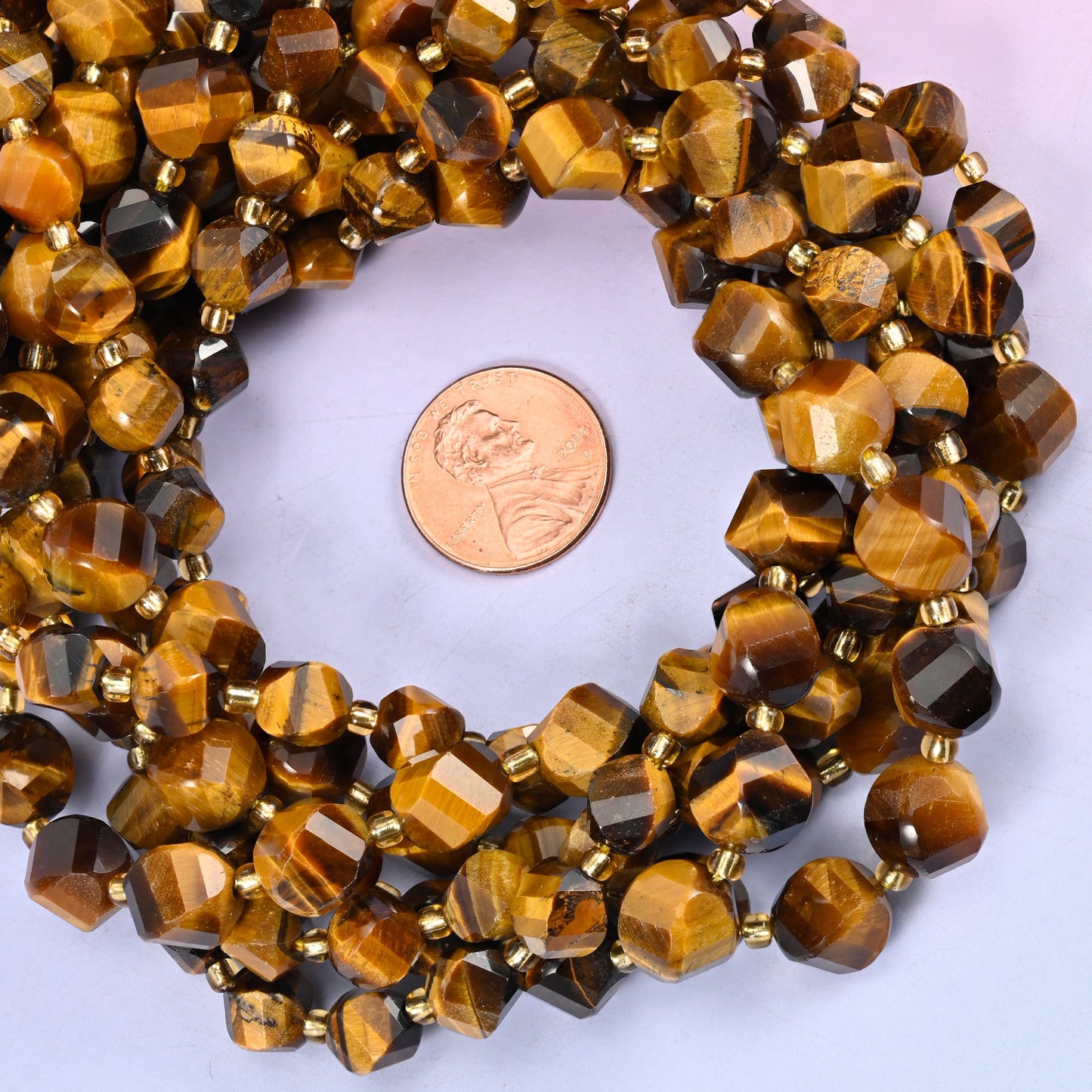 Tiger Eye faceted spiral twist bead strands coiled around a US penny for size reference