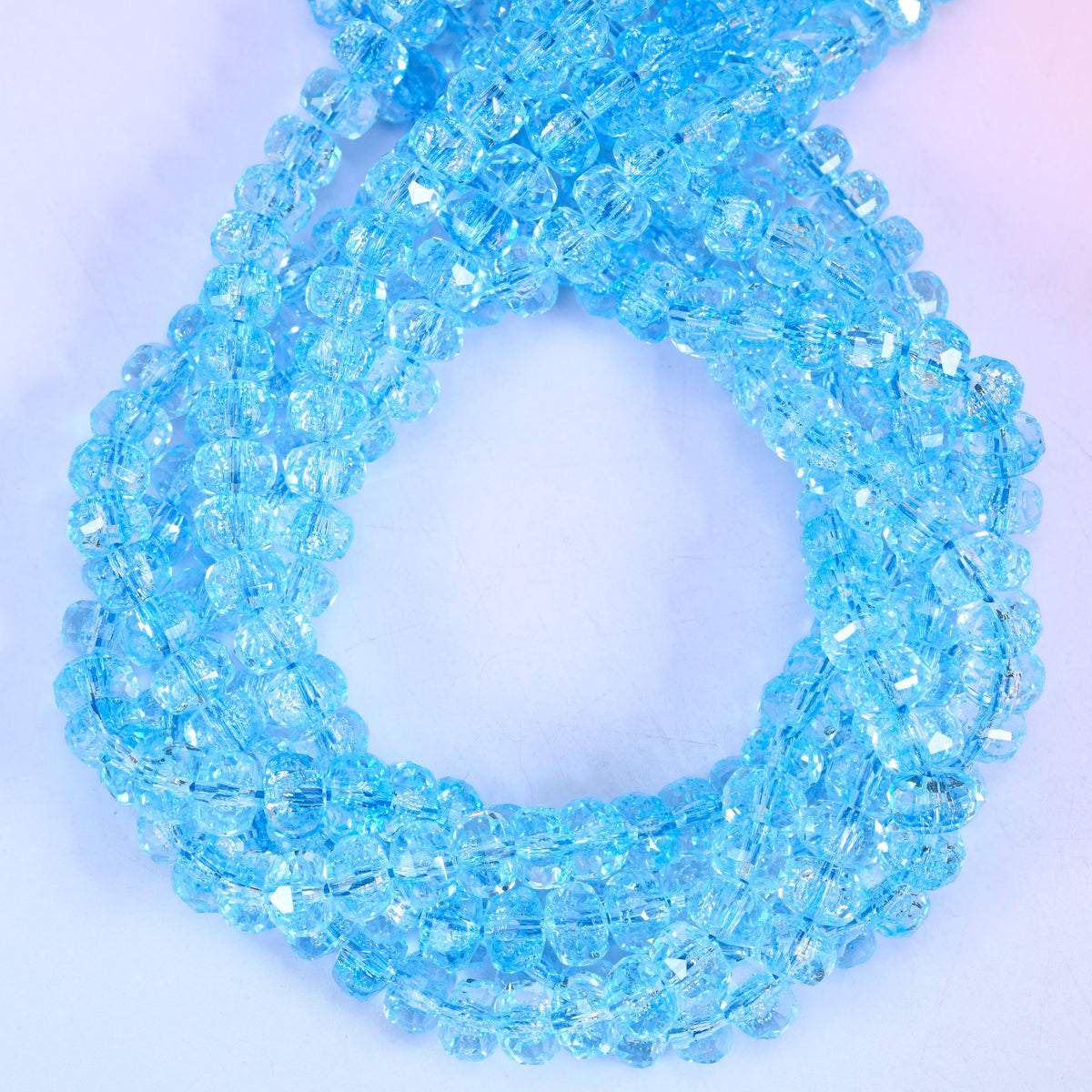 Transparent blue faceted glass rondelle beads, close view of the coiled strands showing clear sky blue