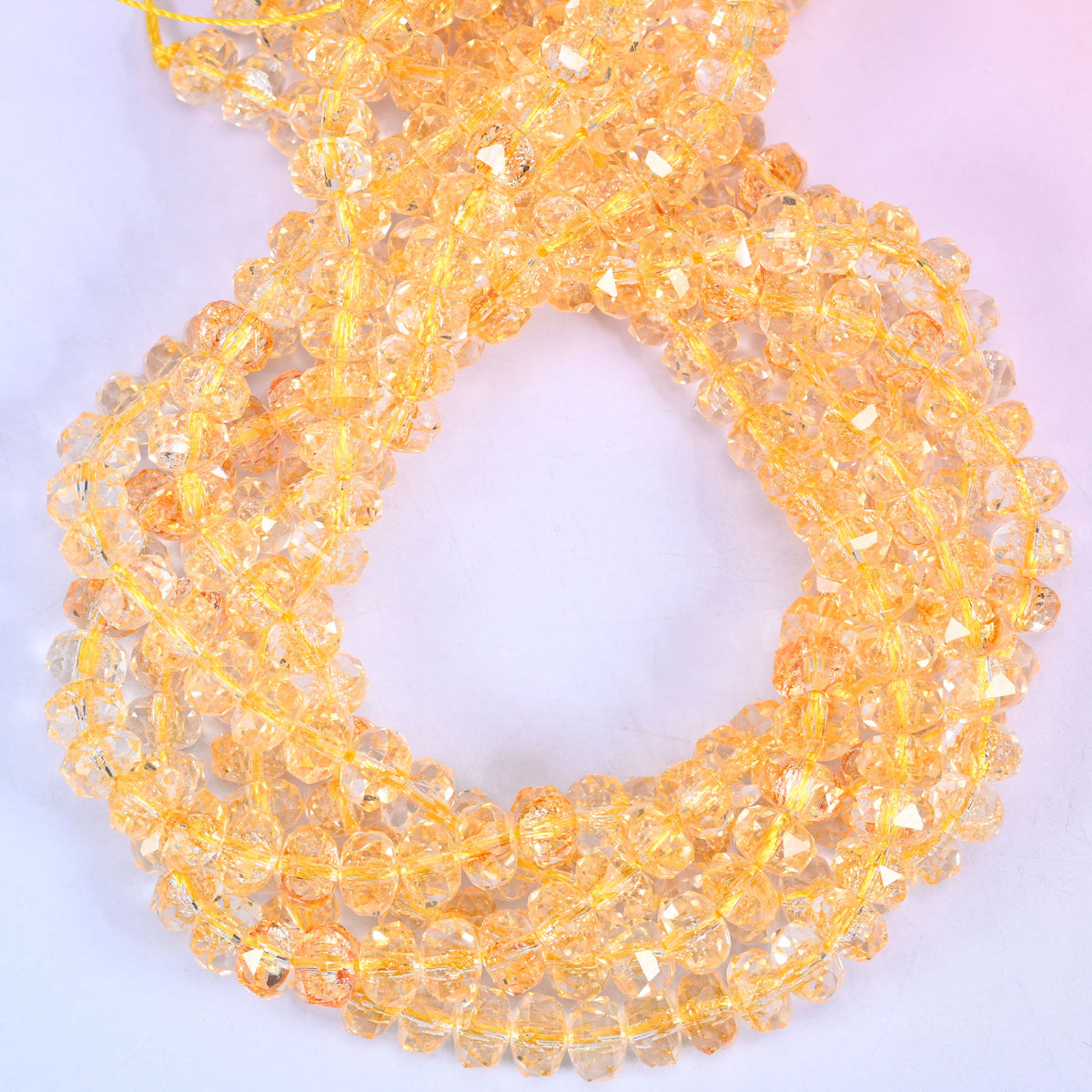 Transparent gold faceted glass rondelle beads, close view of the coiled strands showing clear amber gold