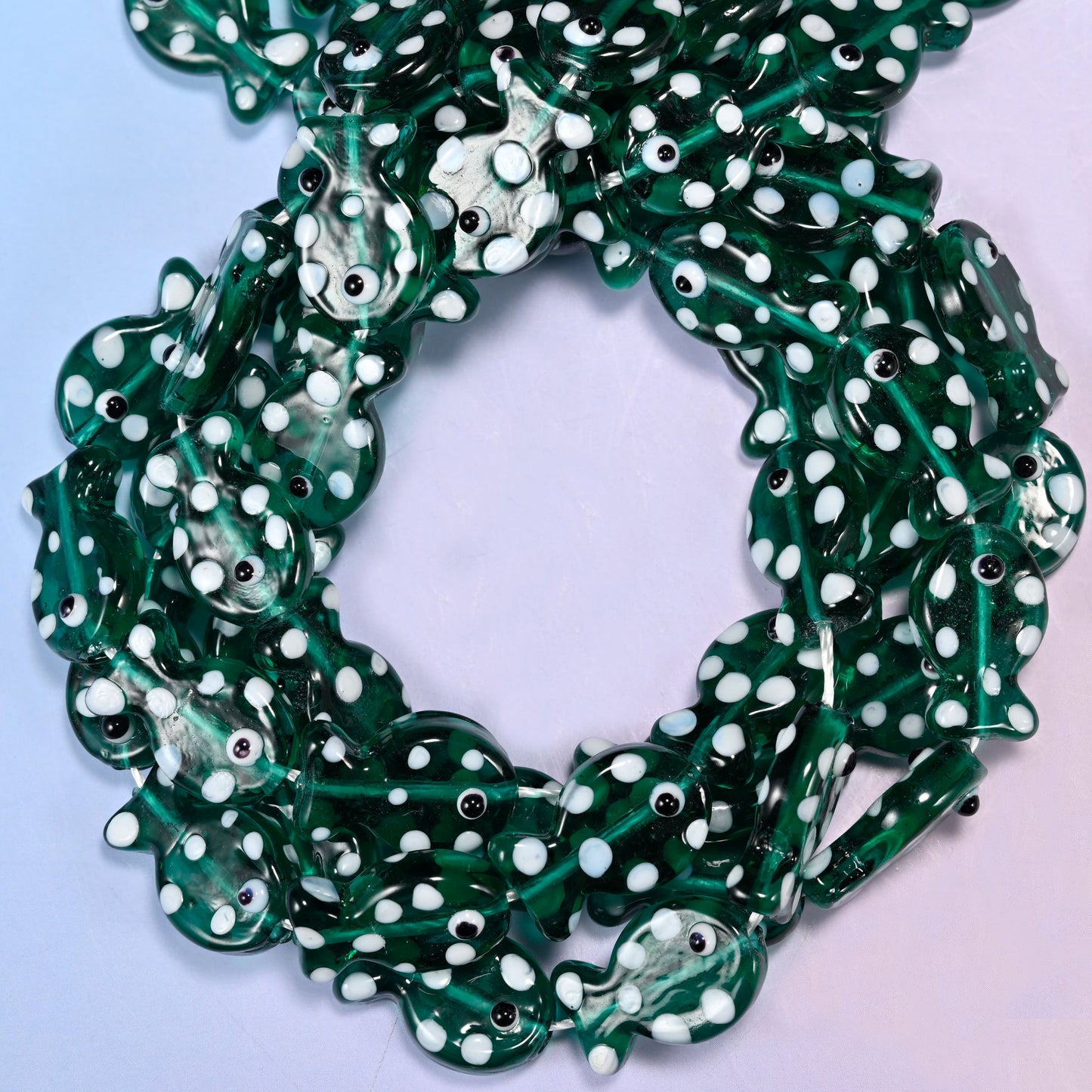 Transparent Jungle Green Fish glass beads, close view of the coiled strands in deep green with white spots