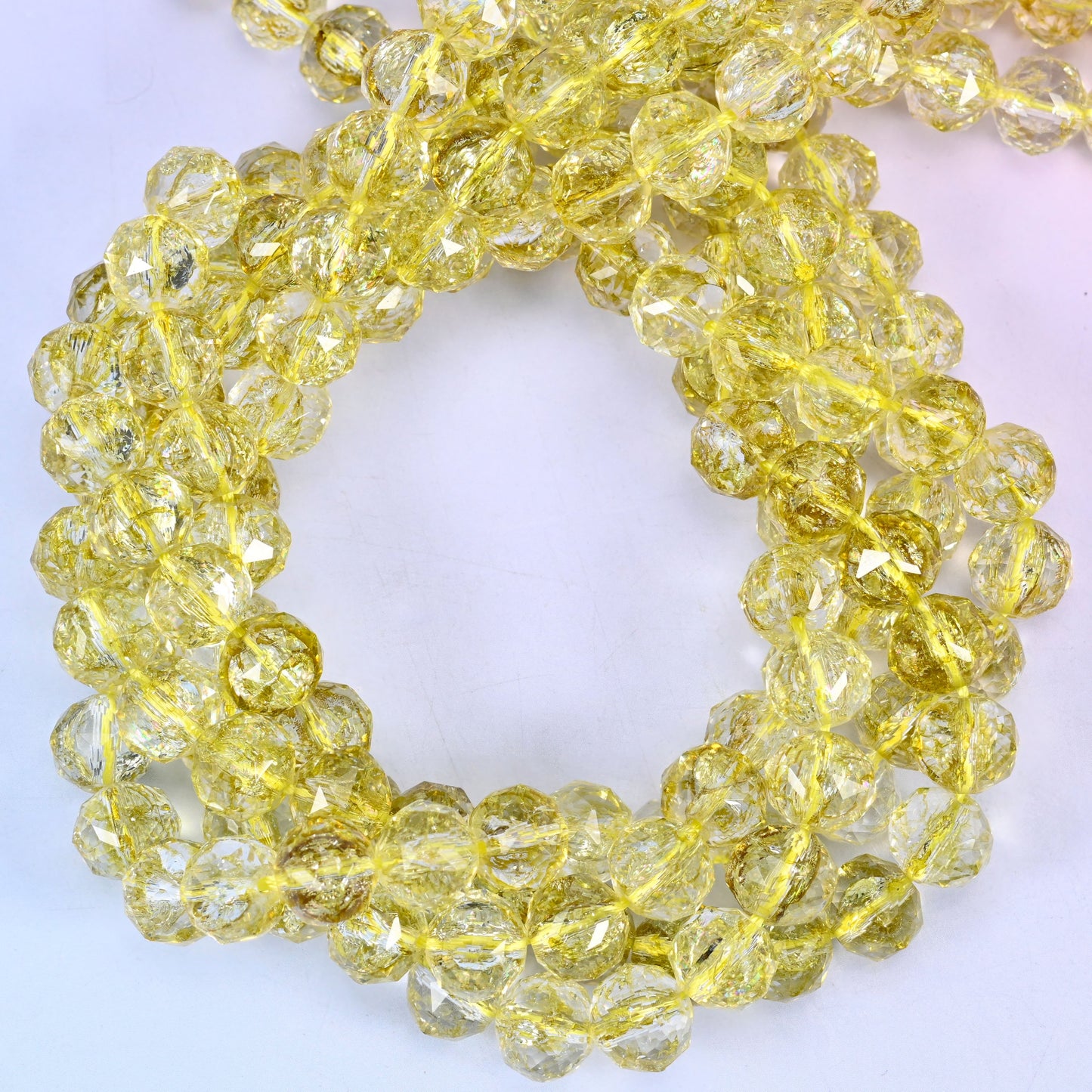 Transparent lemon yellow faceted round glass beads, close view of the coiled strands showing clear lemon yellow