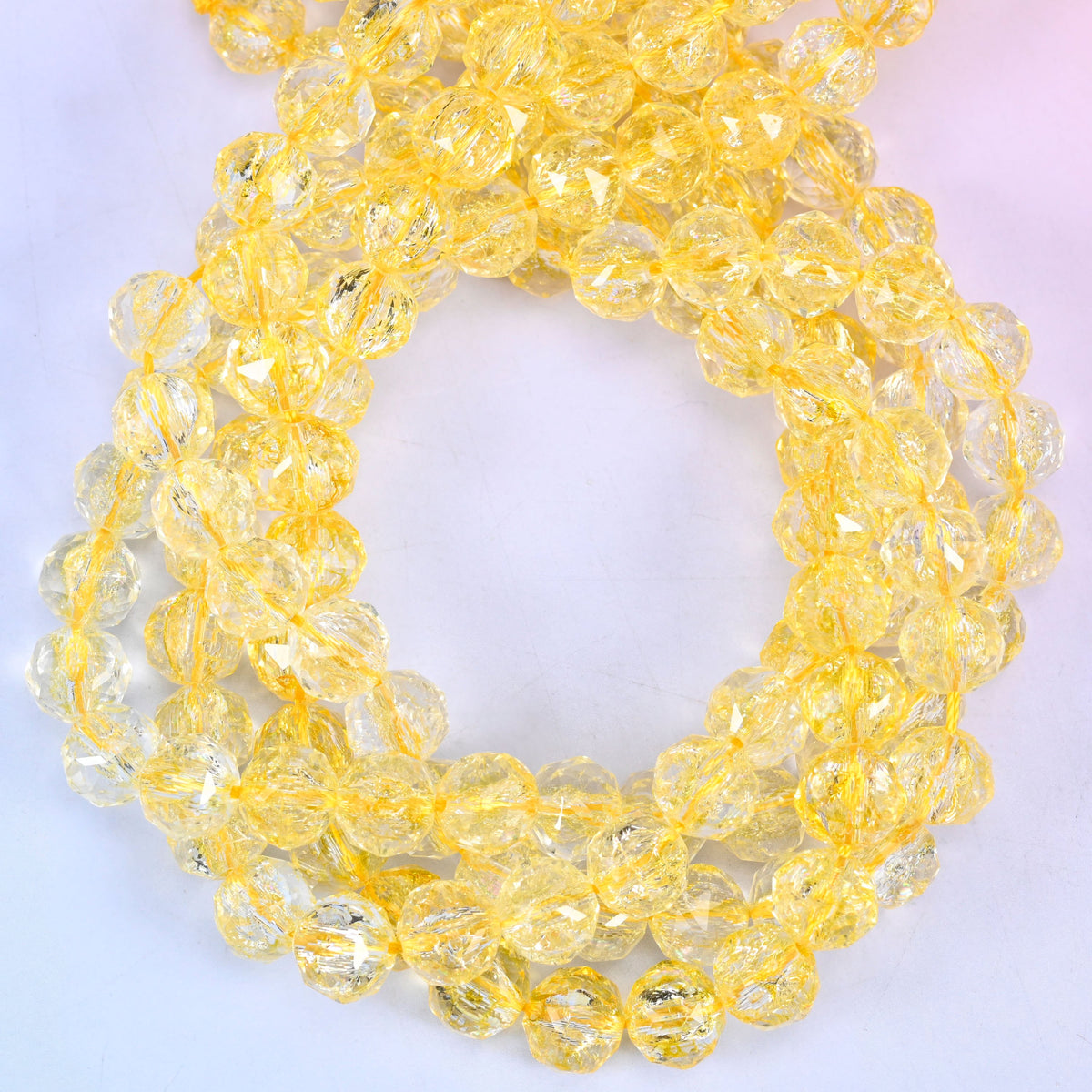 Transparent yellow faceted round glass beads, close view of the coiled strands showing clear golden yellow
