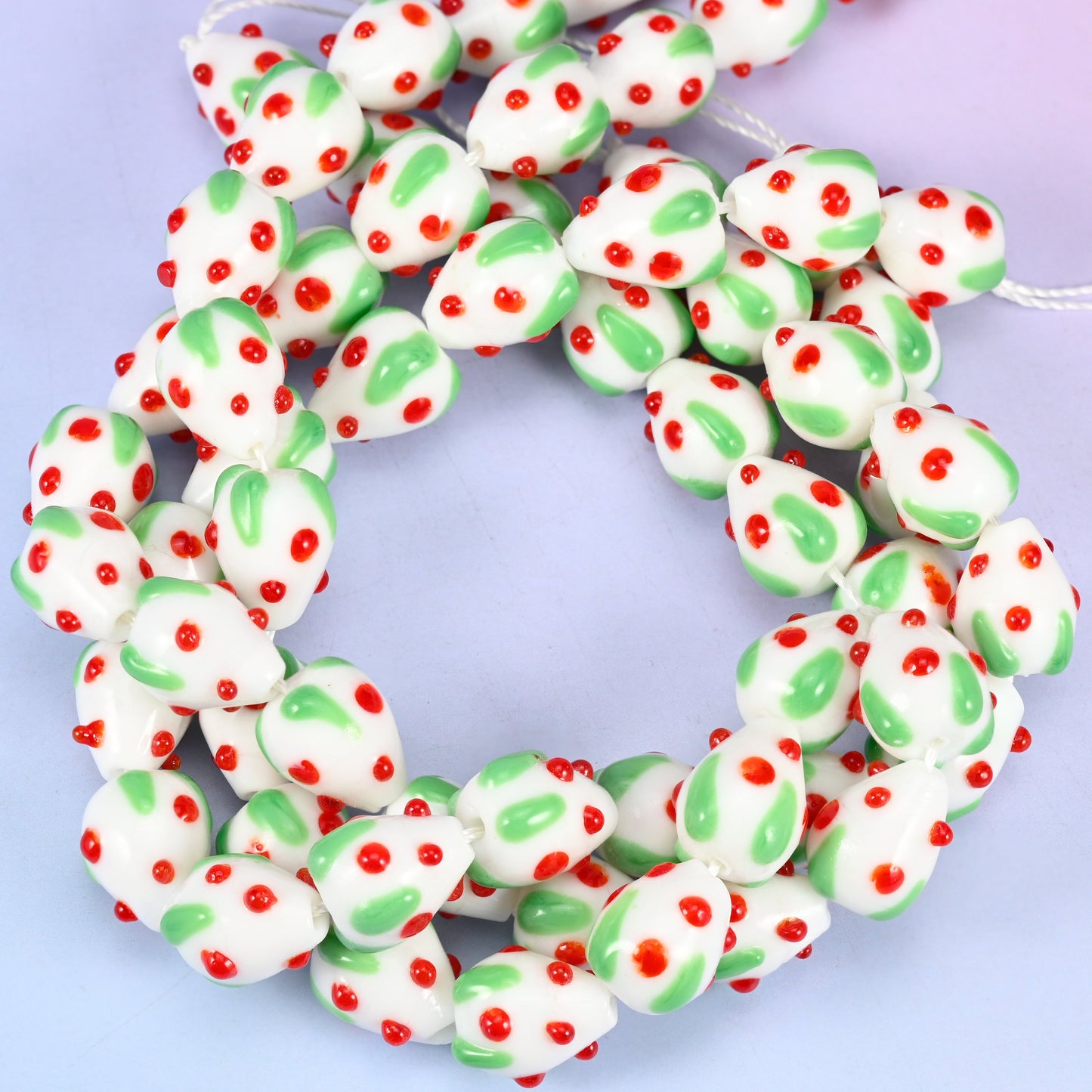 White Red Dots Strawberry glass beads, close view of the coiled strands in white with green leaves and red seed dots